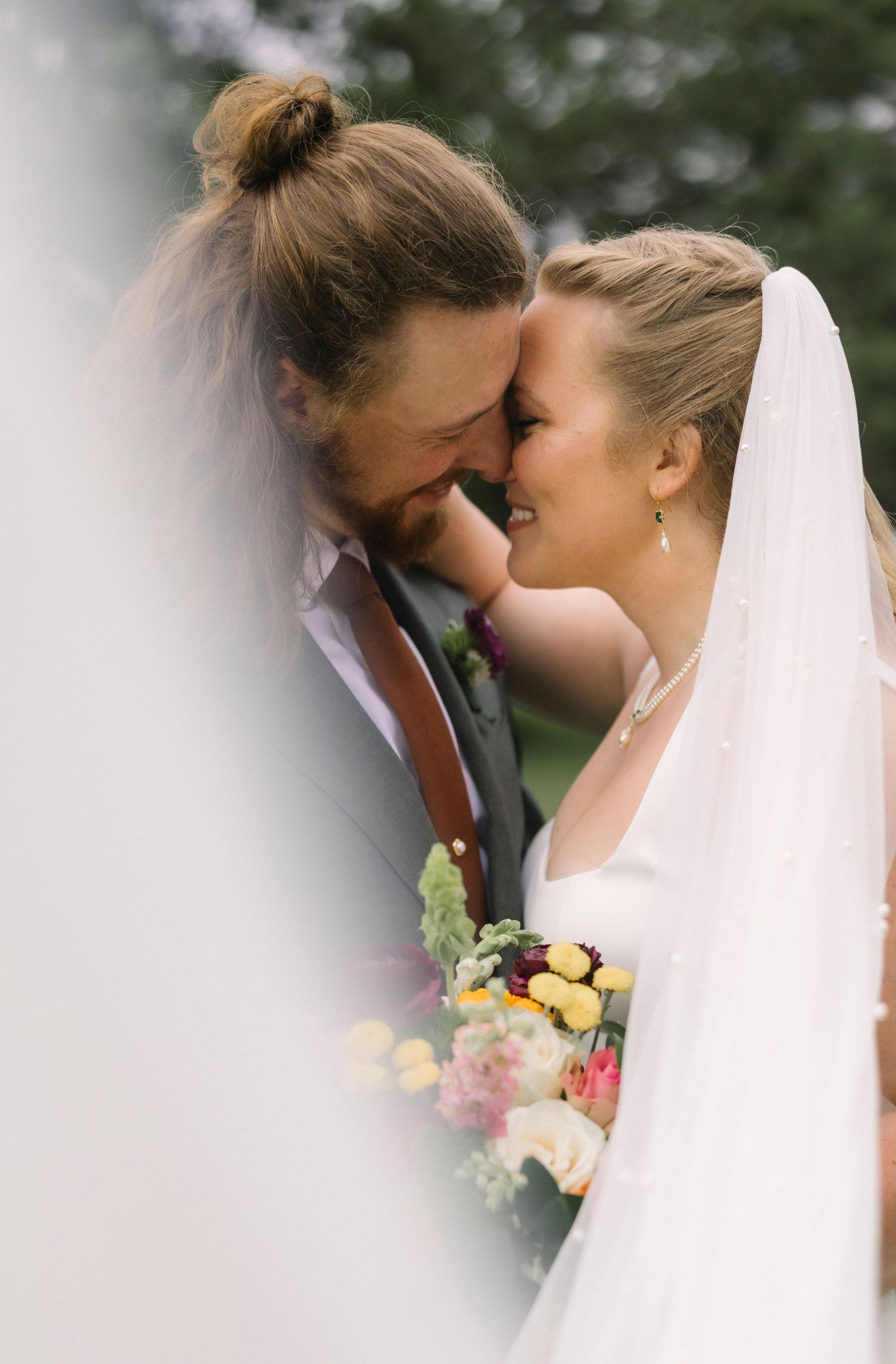 A romantic wedding moment captured through flowers as the couple shares an intimate kiss.