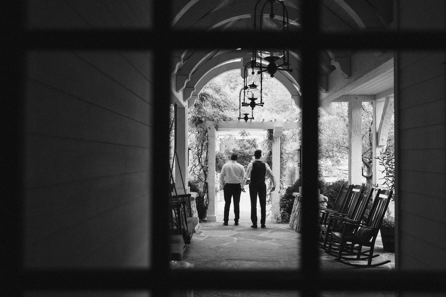 Silhouettes of wedding party members frame a dark archway entrance.