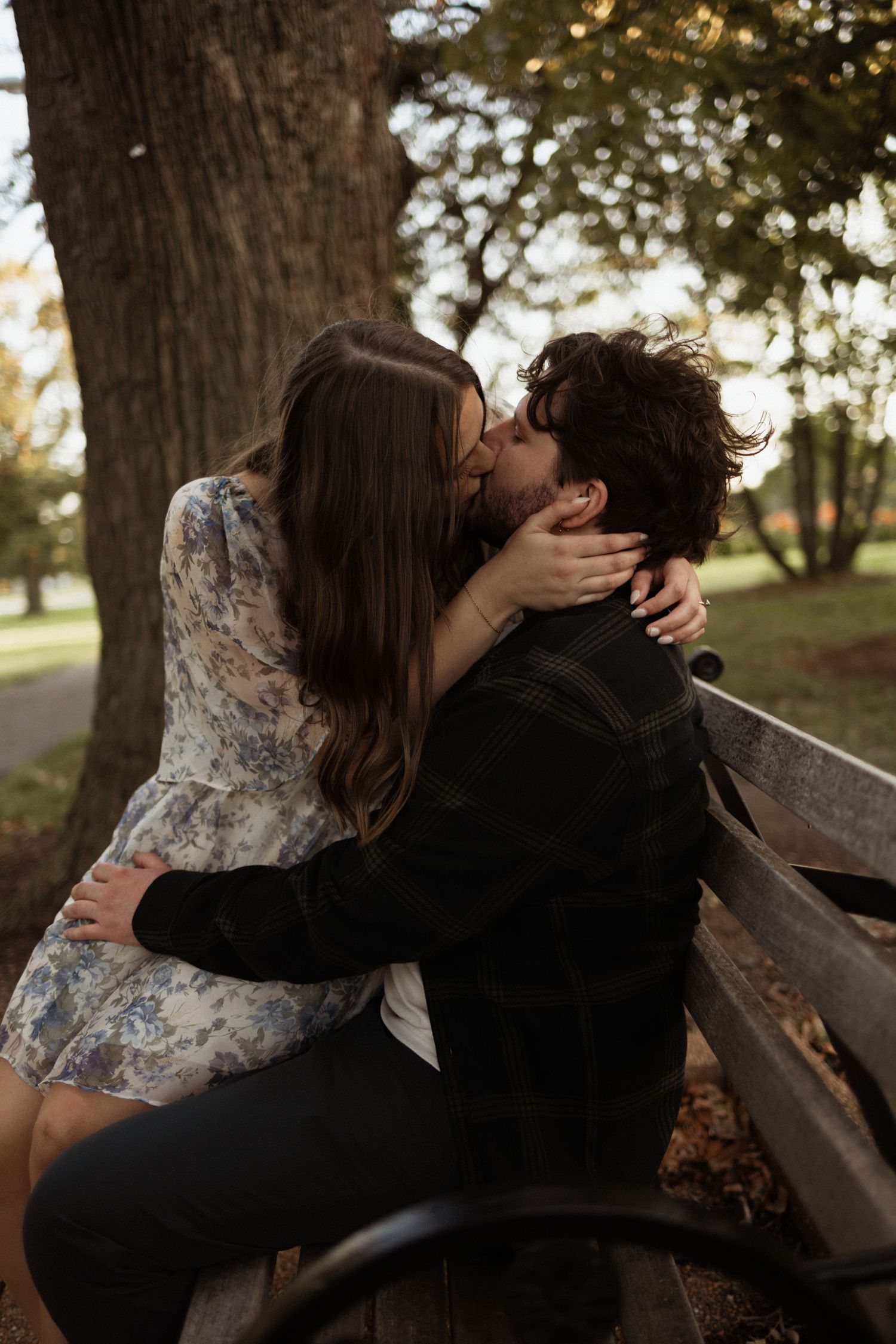 A romantic scene on a park bench surrounded by autumn trees.
