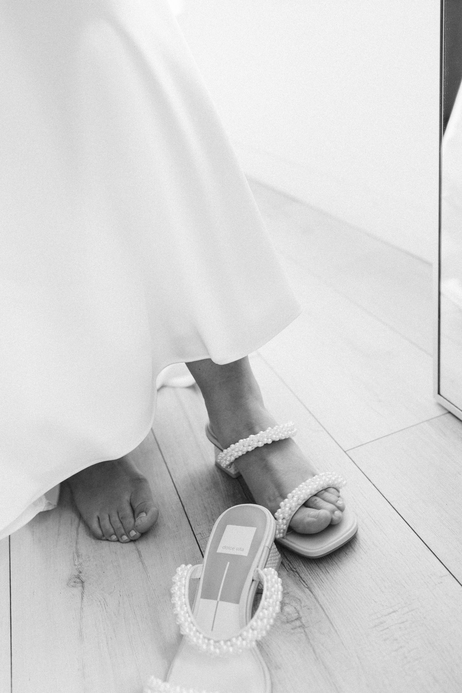 Close-up view of bare feet and hands on white floor playing with UNO cards during a casual game.