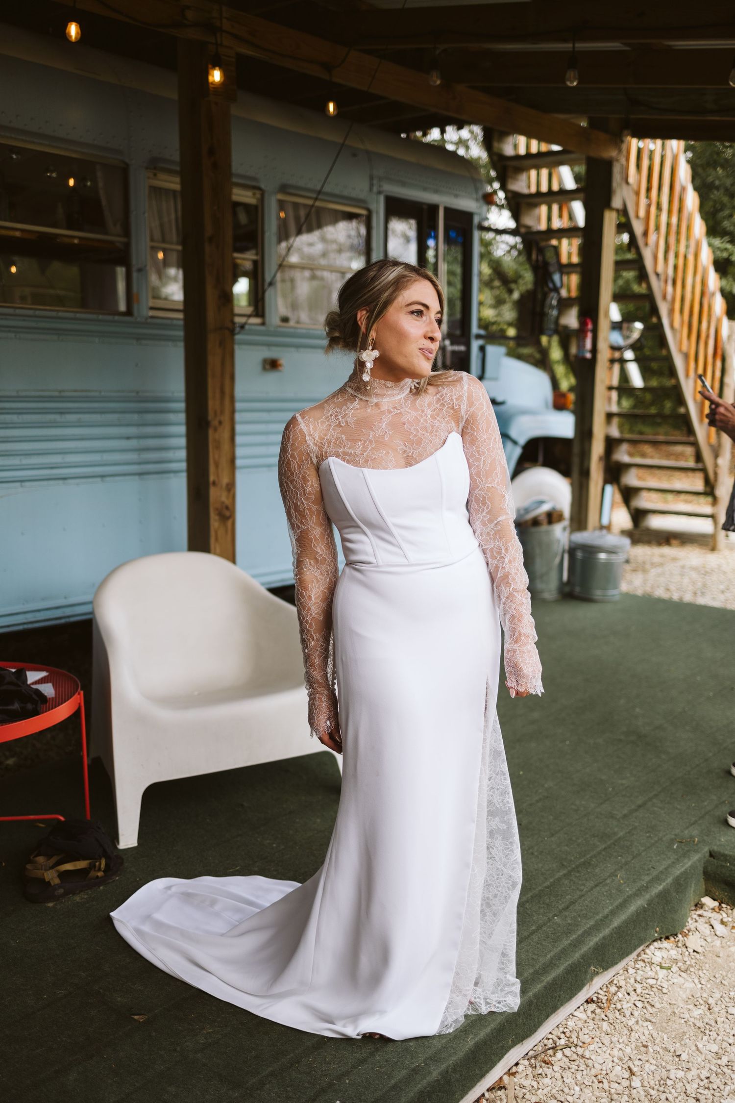 A flowing white wedding gown with delicate lace details is showcased on a rustic wooden porch.