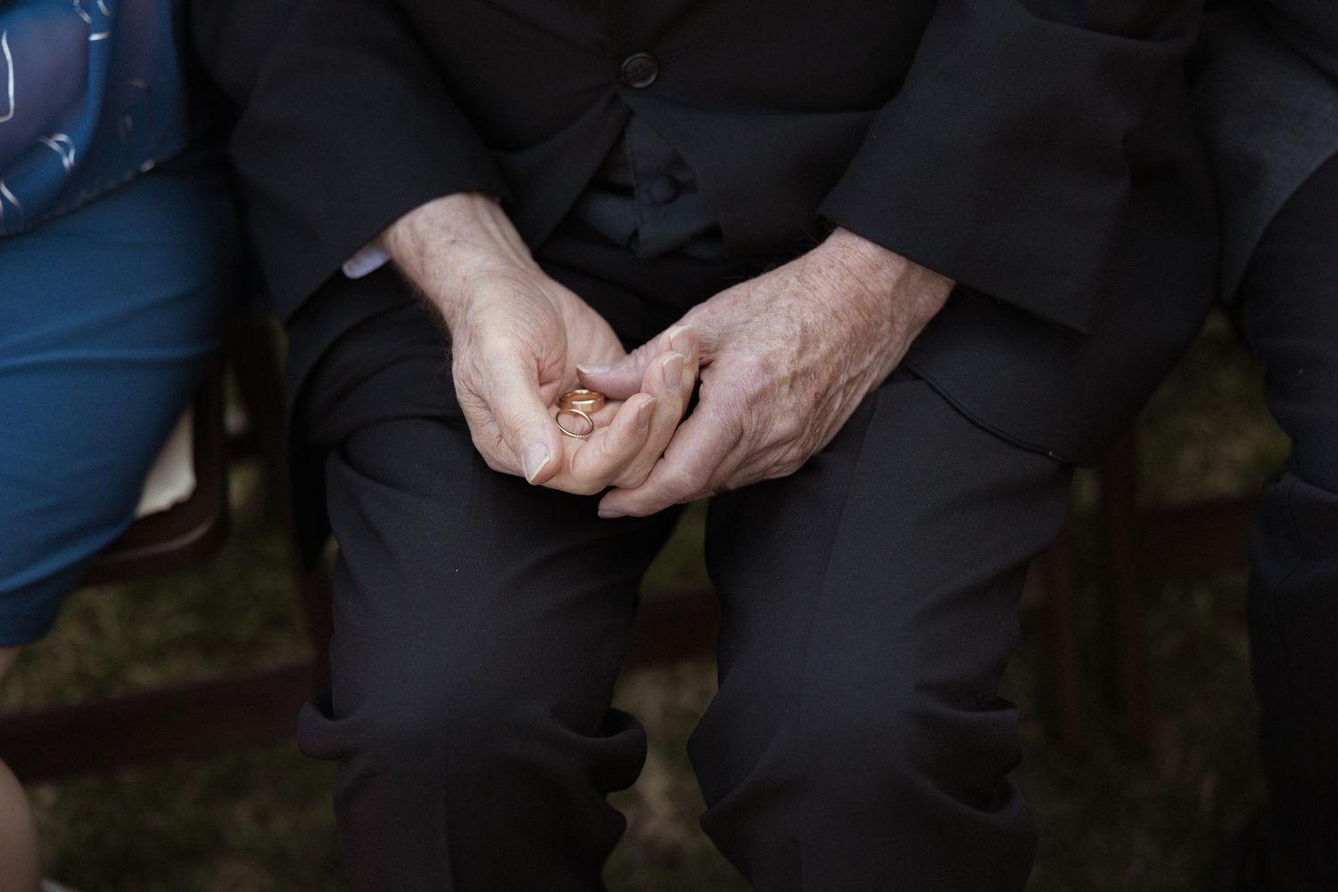 A person wearing black dress pants reaches down to adjust or check something at their feet.