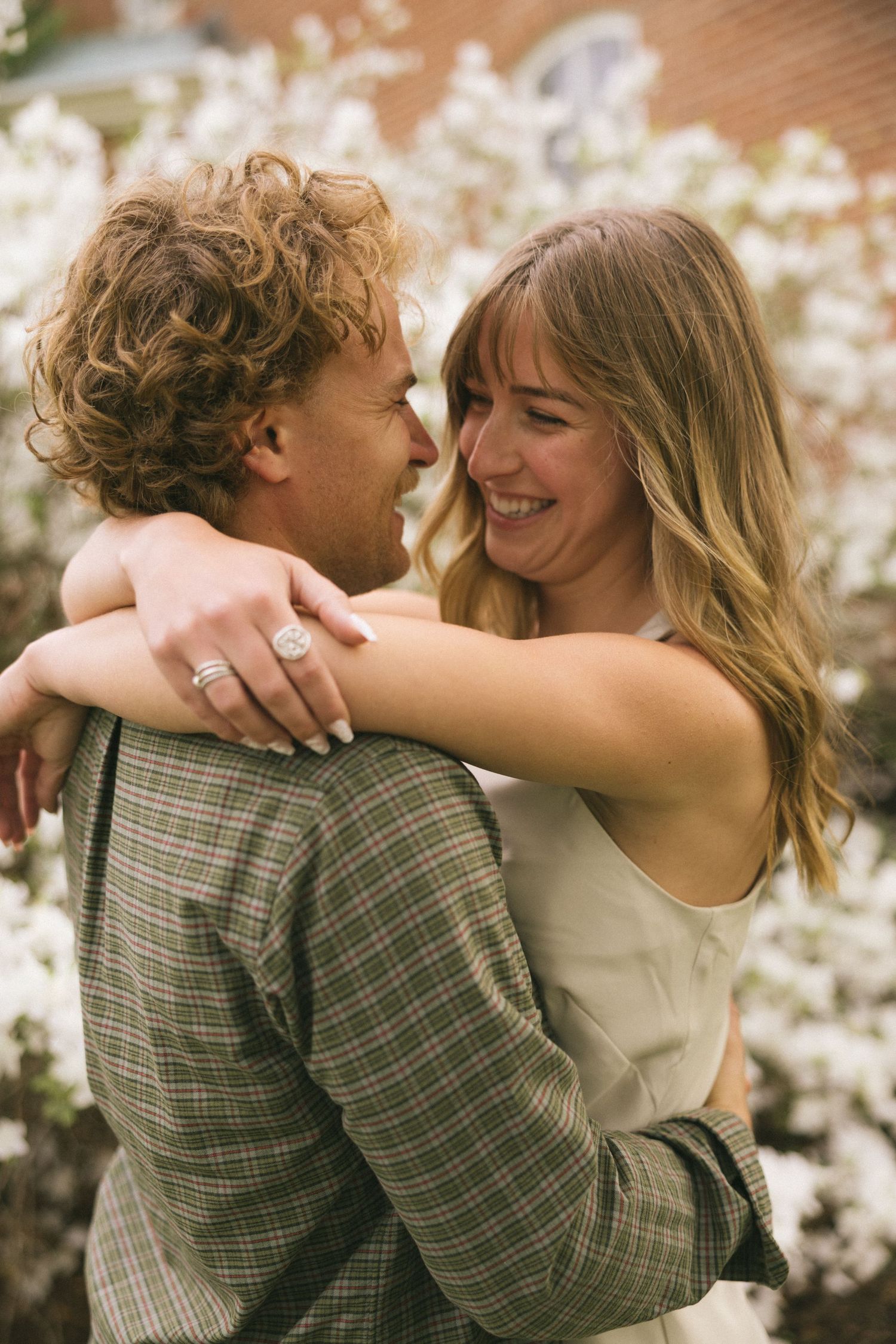 Romantic couple embracing among blooming white flowers.