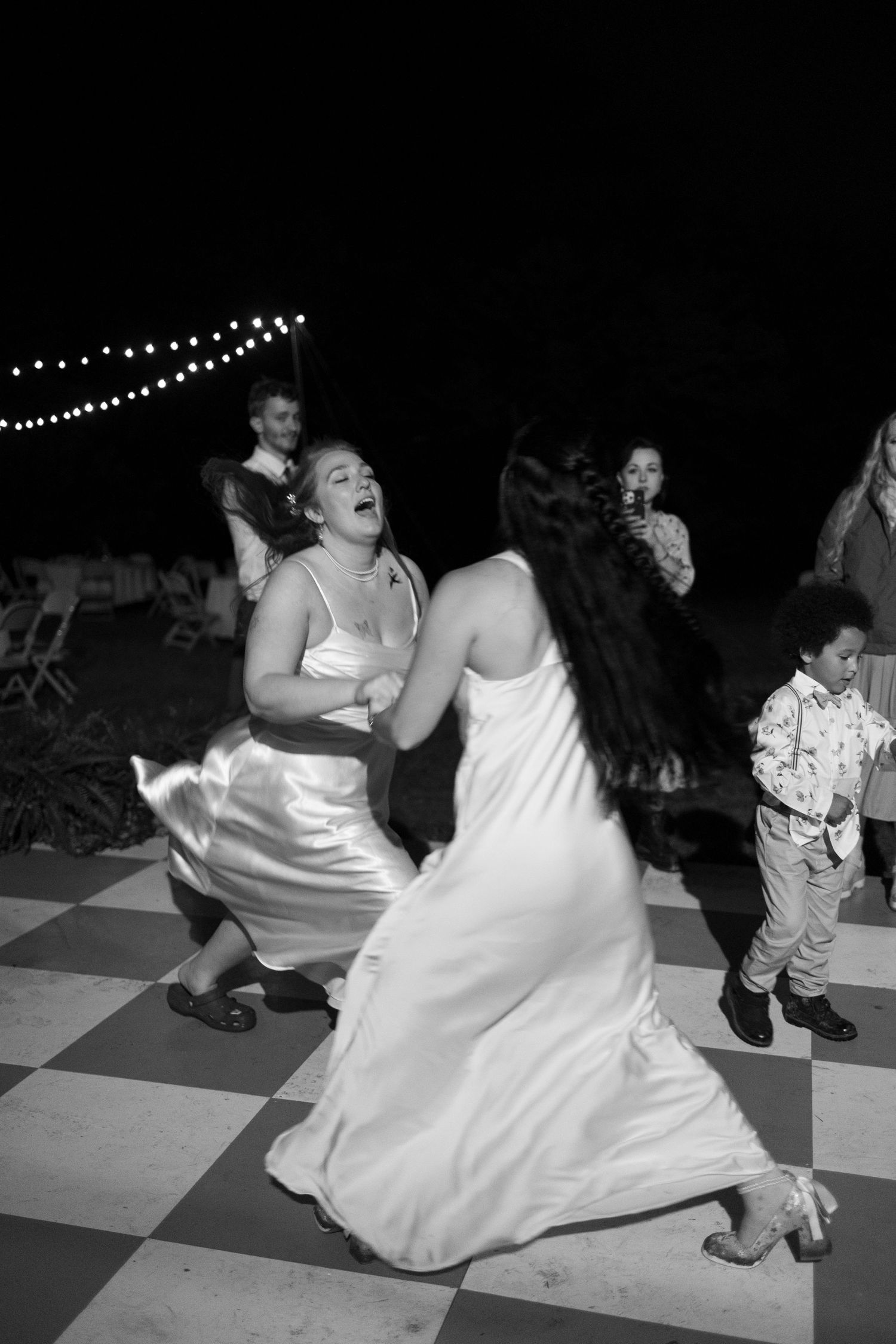 Black and white photos show a couple dancing joyfully on a checkerboard dance floor at a celebration.