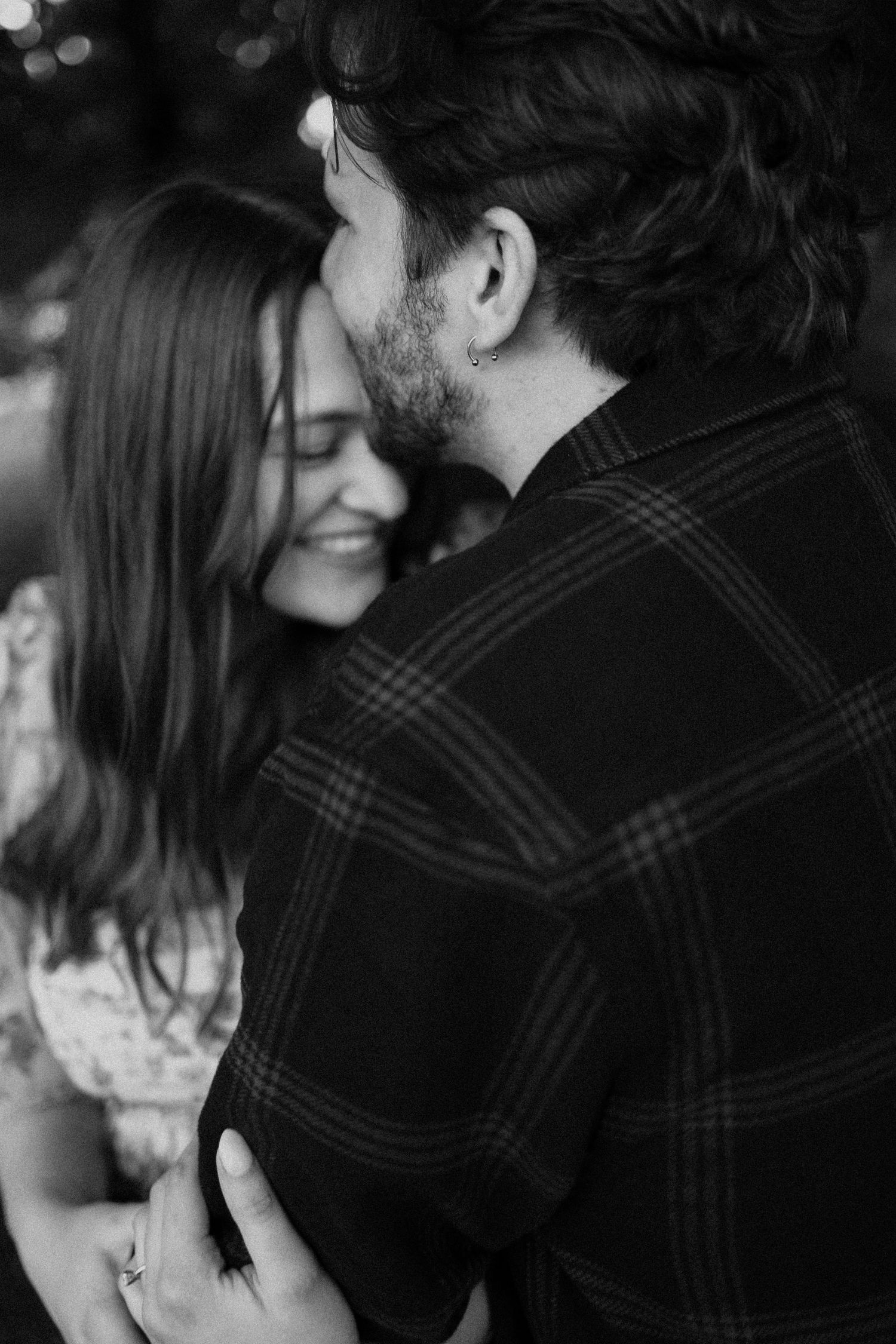 A romantic black and white photo of a couple sharing an intimate moment in a plaid flannel and dress.