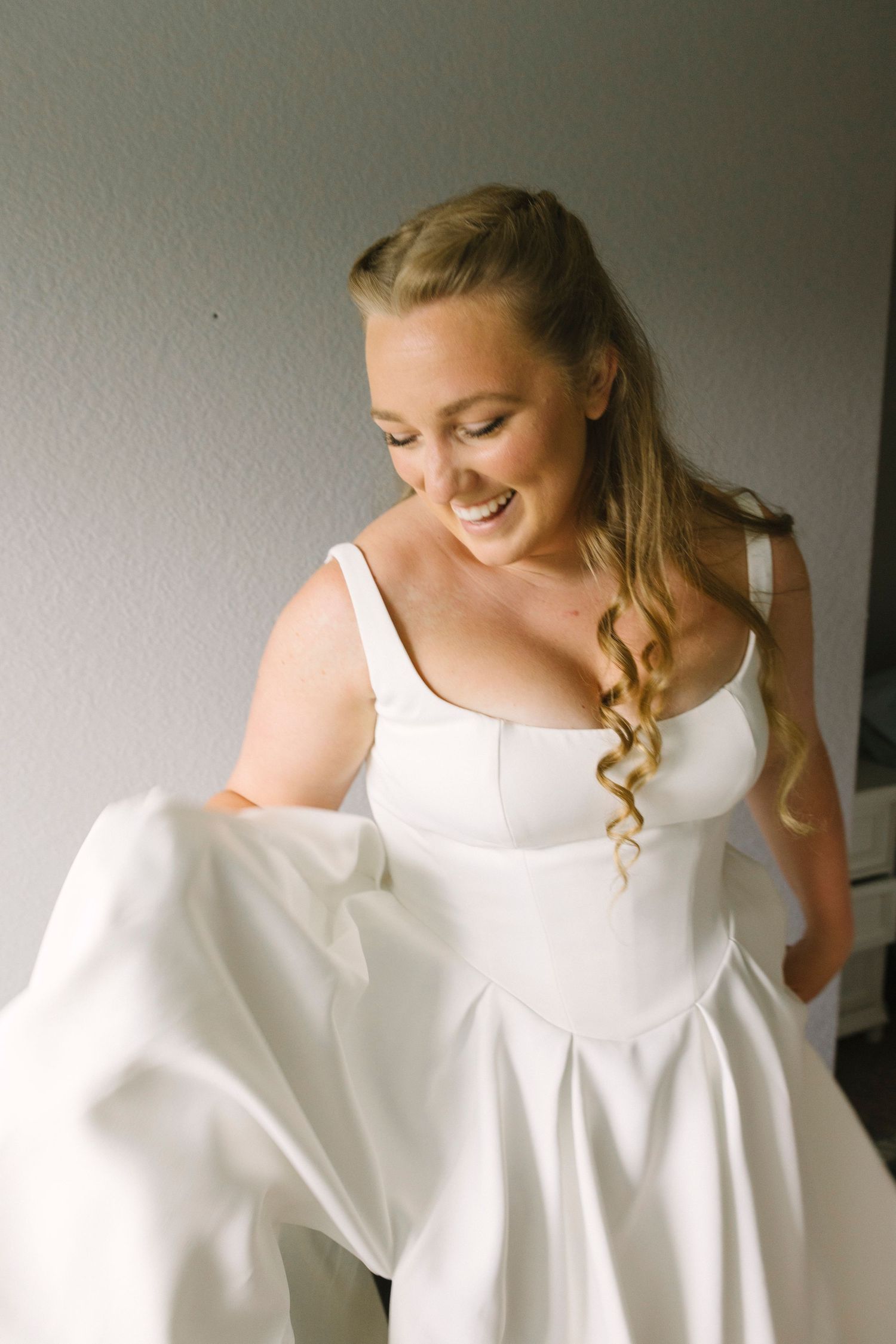 A candid moment of someone in a classic white wedding dress showing joy and excitement.