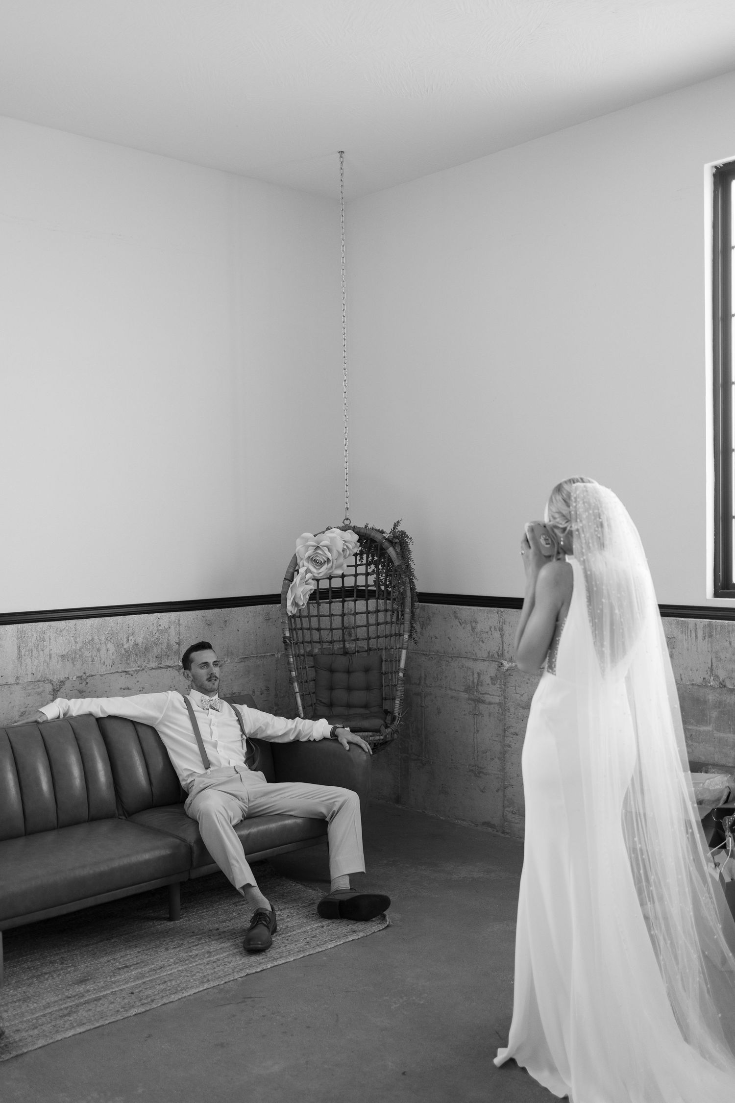 Black and white photo of couple sharing first look moment in minimalist venue room.