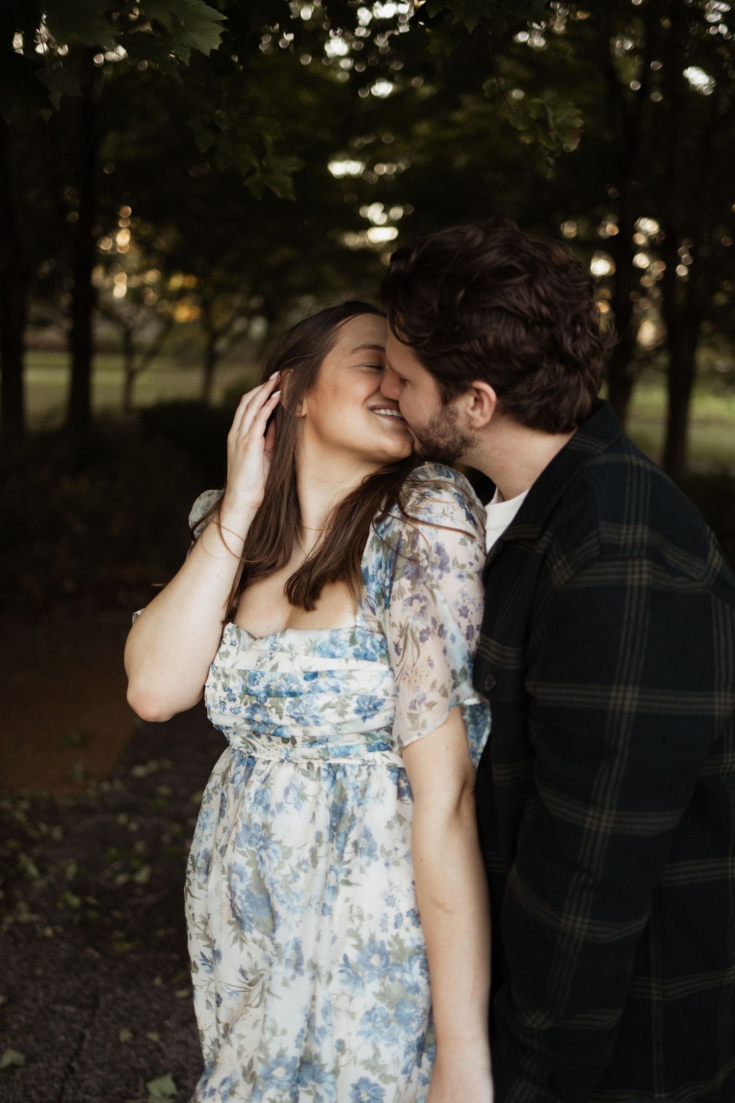 A candid moment of laughter and affection in a wooded setting.