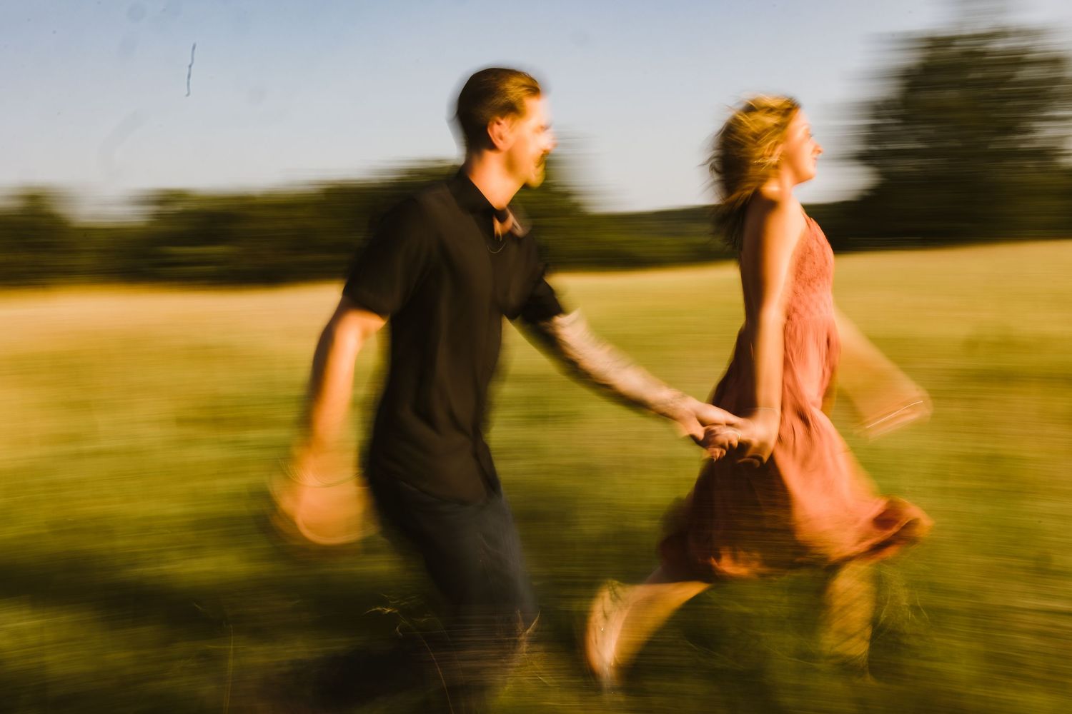 Motion-blurred artistic sequence of a couple running through a sunlit field.