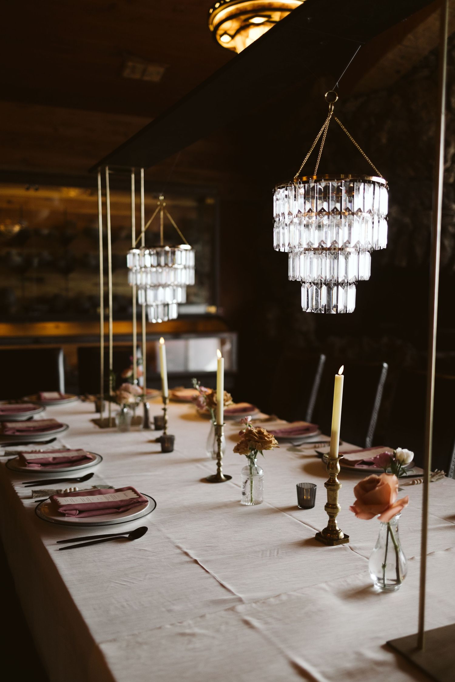 Elegant wedding reception table with crystal chandeliers and candlesticks.