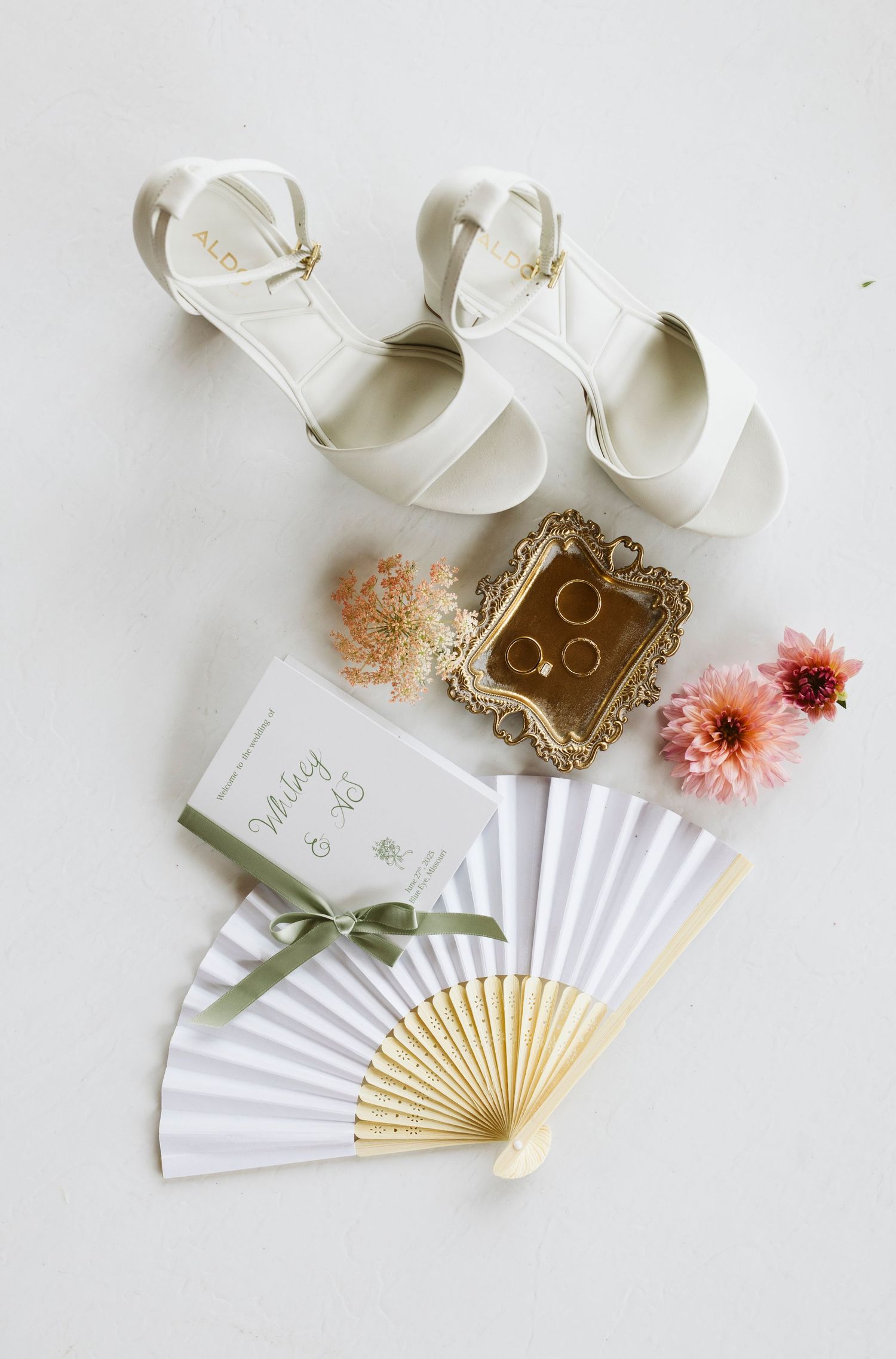 Elegant white paper hand fans with vintage gold trim and soft pink floral accents displayed on white surface.
