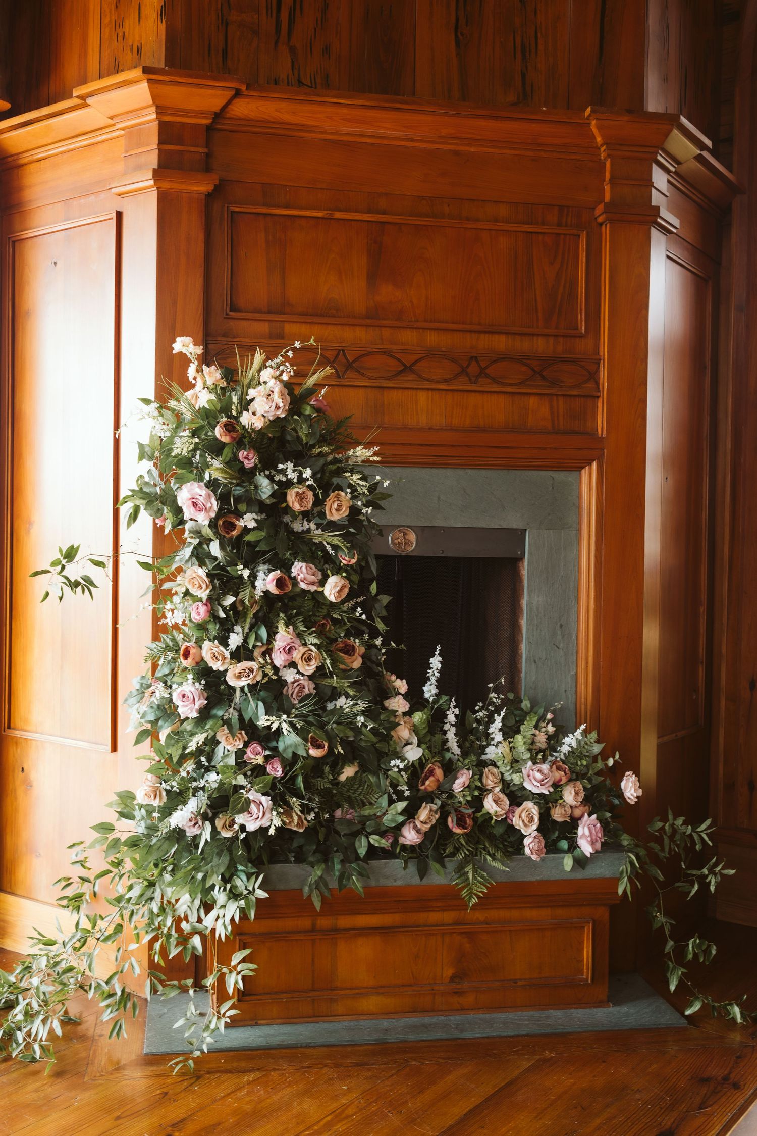 Elegant floral arrangement with pink roses adorns a wooden wall panel in rustic interior.