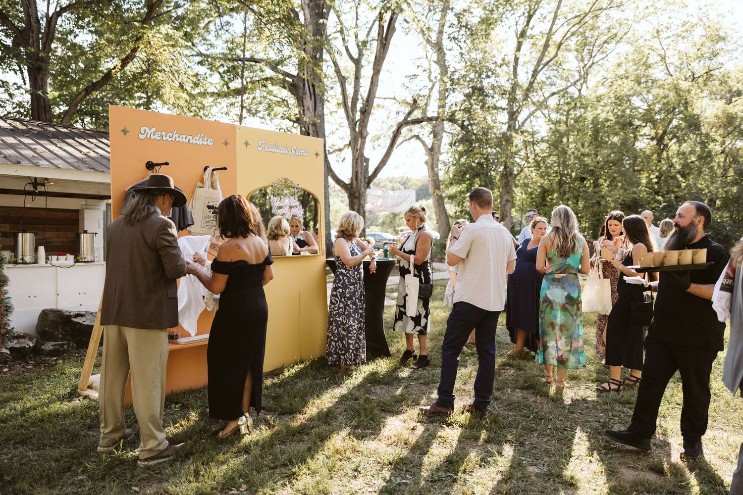 Guests mingling during an outdoor garden party with natural lighting and trees.
