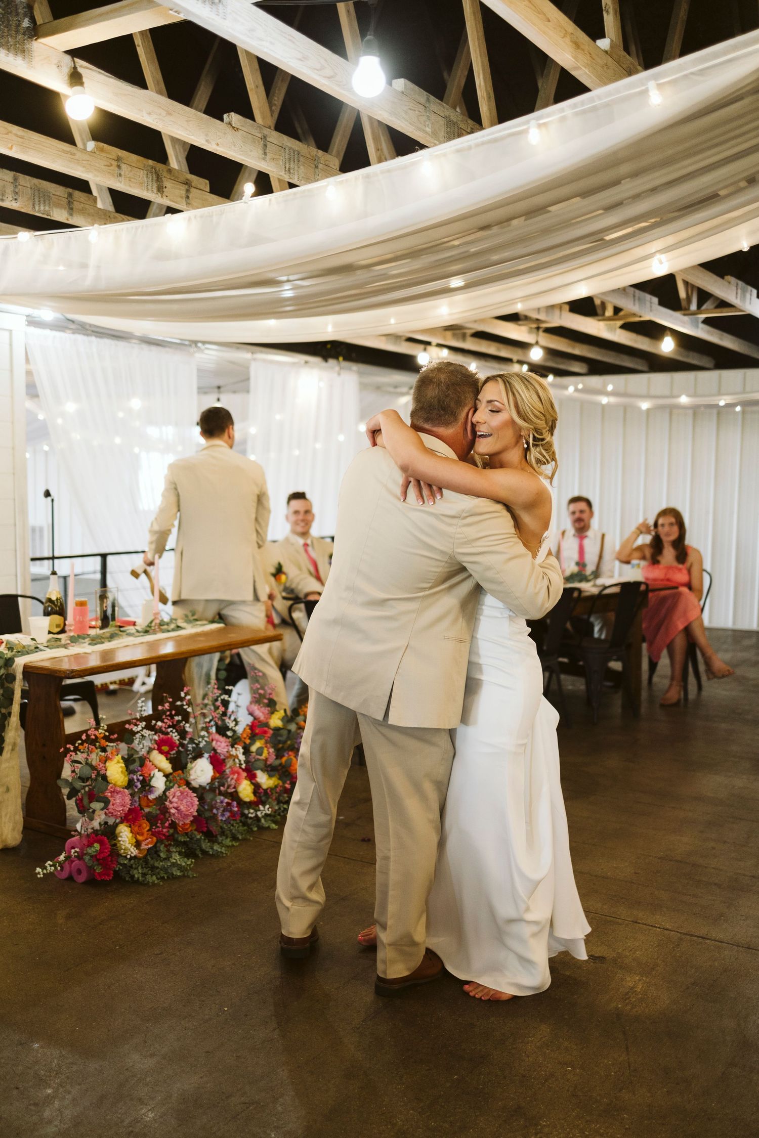 Wedding reception venue with couples dancing and white draped ceiling decorations.