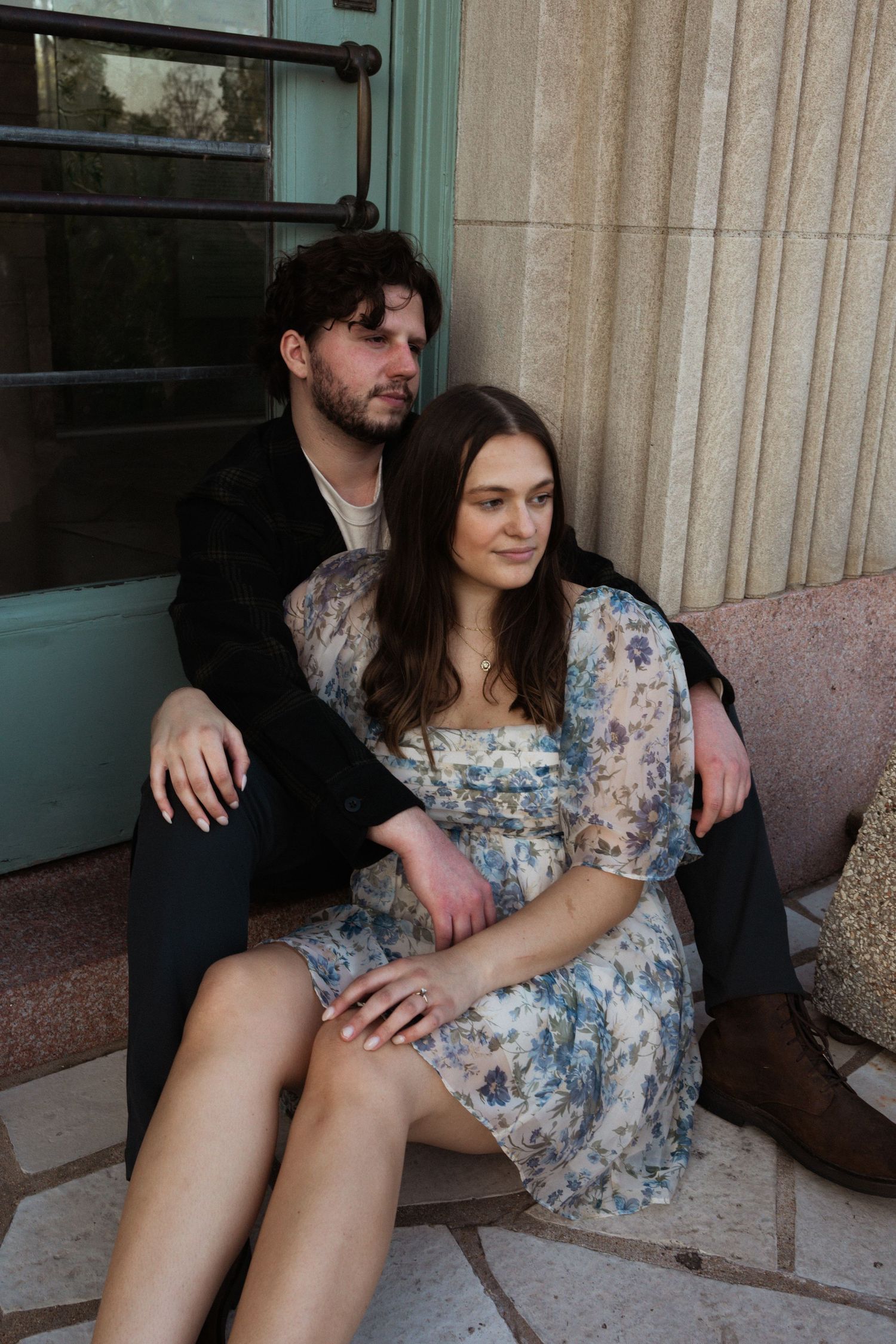A couple sitting close together on outdoor steps in coordinated outfits.