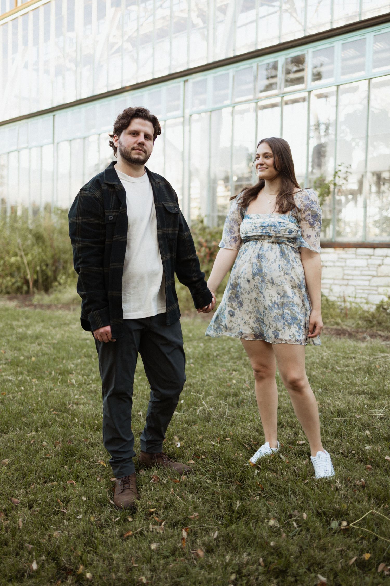 A couple in casual attire standing together by a glass building exterior.