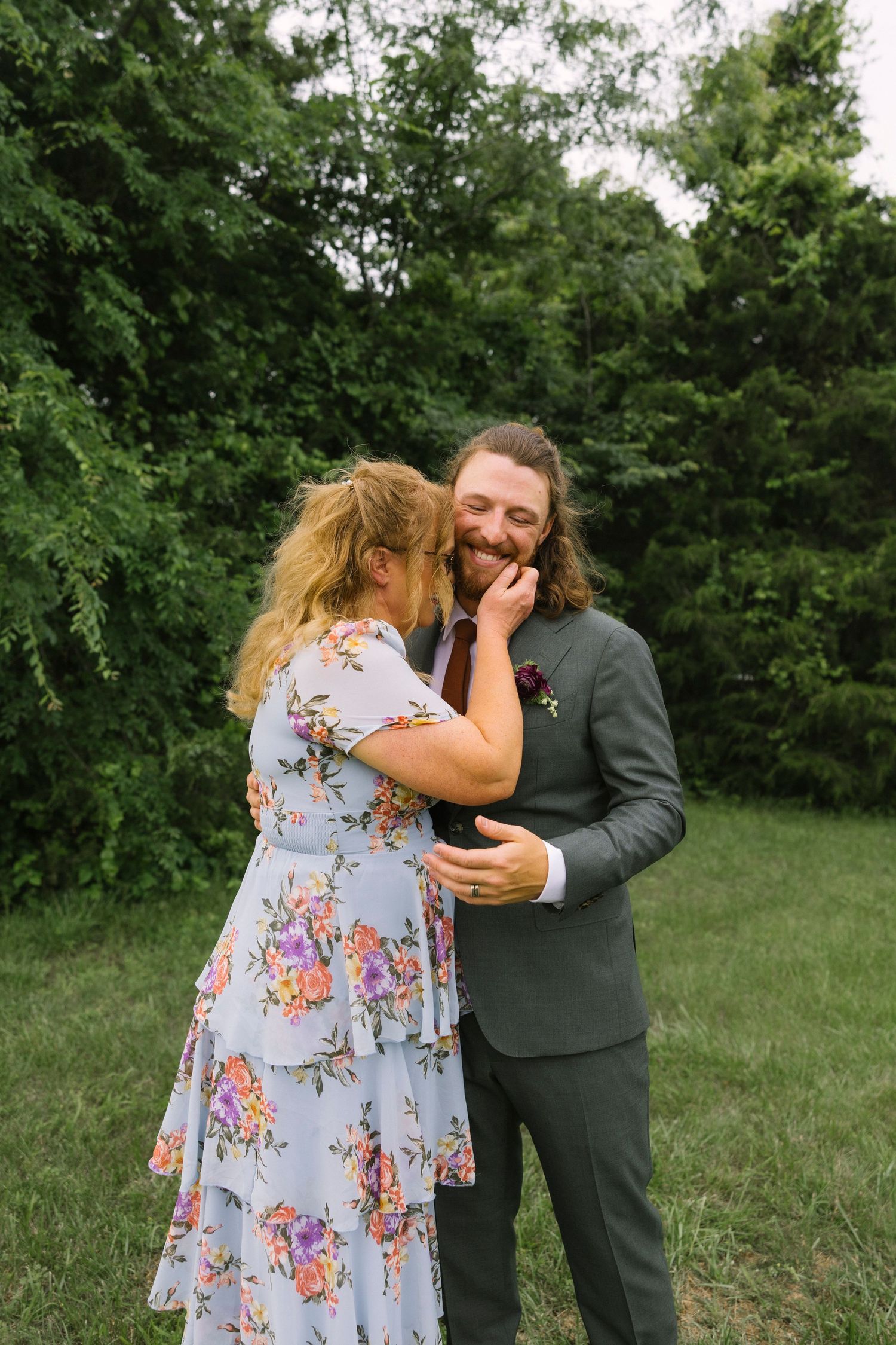A tender moment shared between a couple in a garden setting, with the woman in a floral dress.