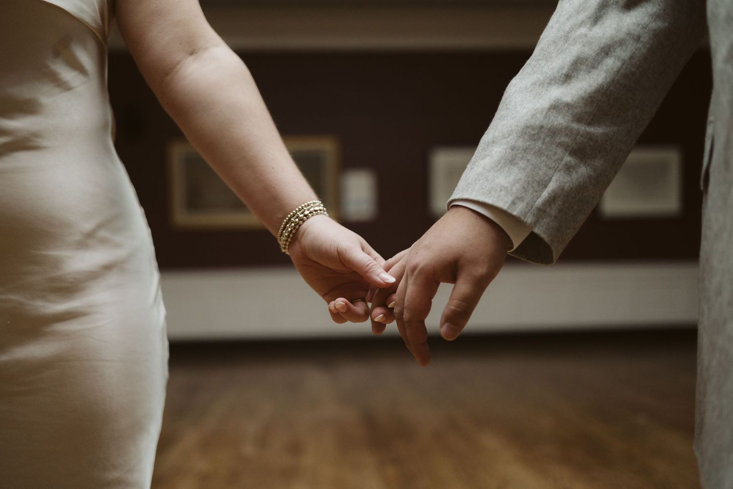 Close-up of two hands gently touching in a romantic moment against a wooden floor background.