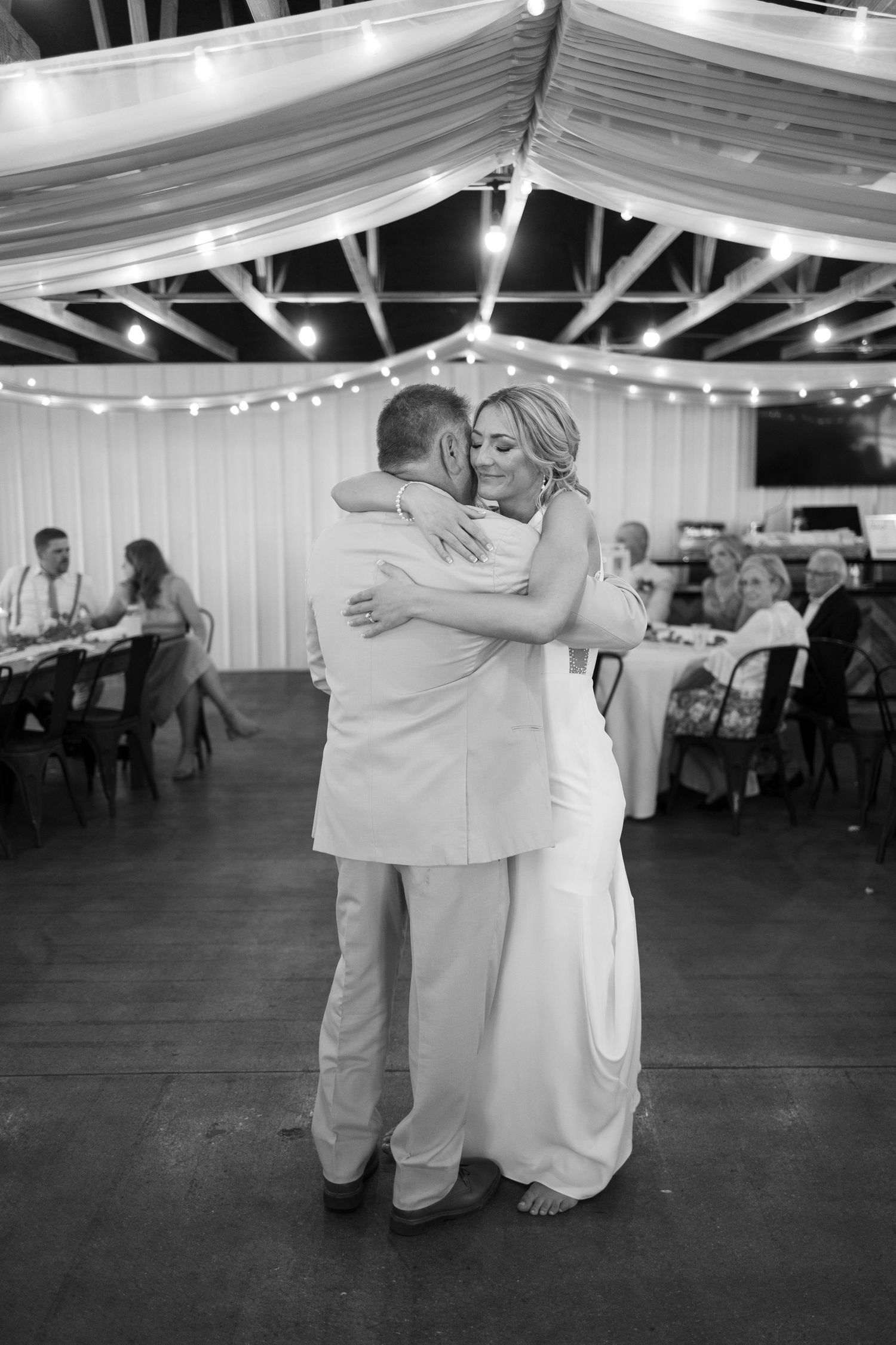 Couples dancing together at a wedding reception venue under white fabric ceiling decorations.