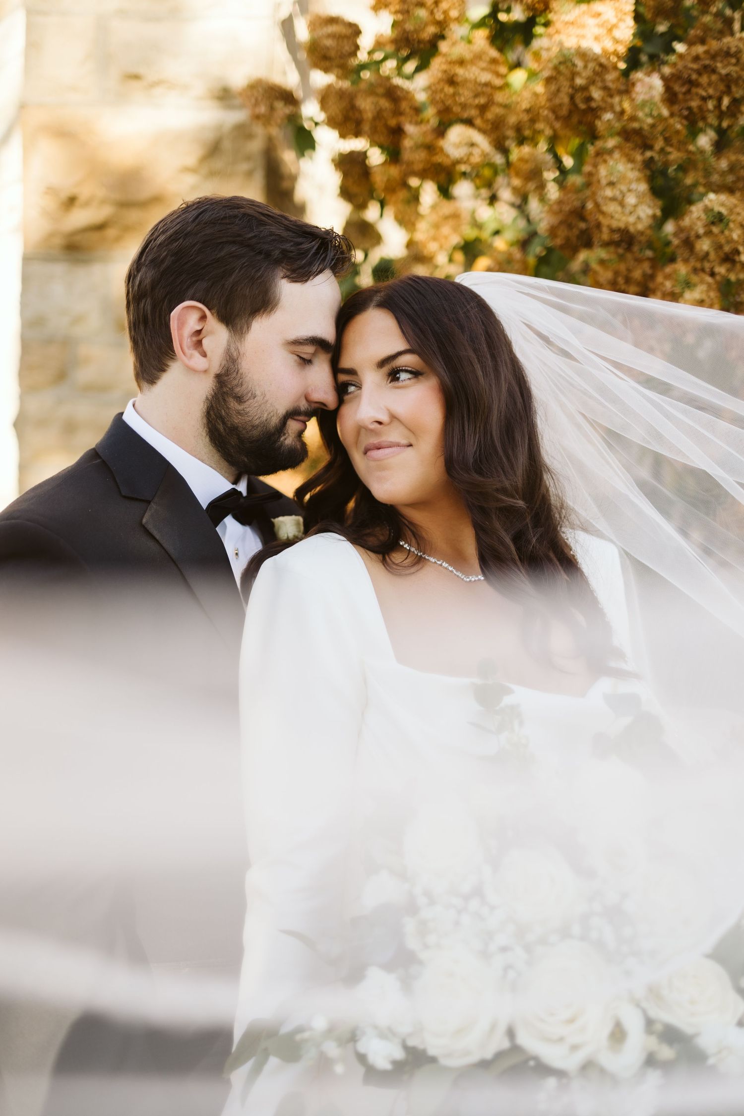 A romantic portrait of newlyweds sharing an intimate moment under a flowing veil.