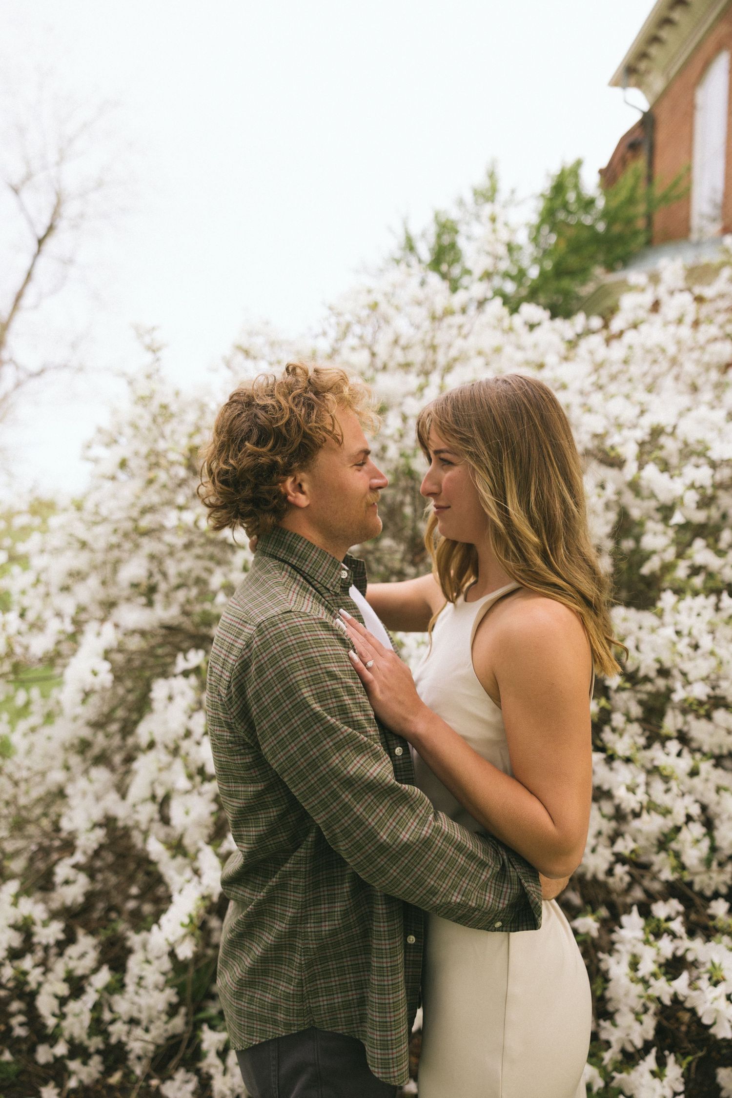A tender moment between a couple against a background of blooming white spring flowers.