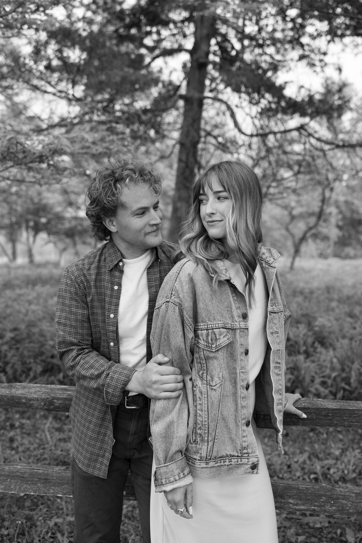 Black and white portrait of couple in casual wear outdoors among trees.