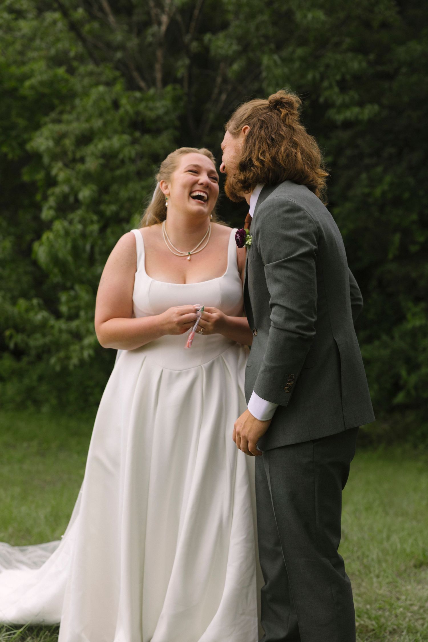 A joyful wedding moment captured outdoors as a couple shares a laugh together on their special day.