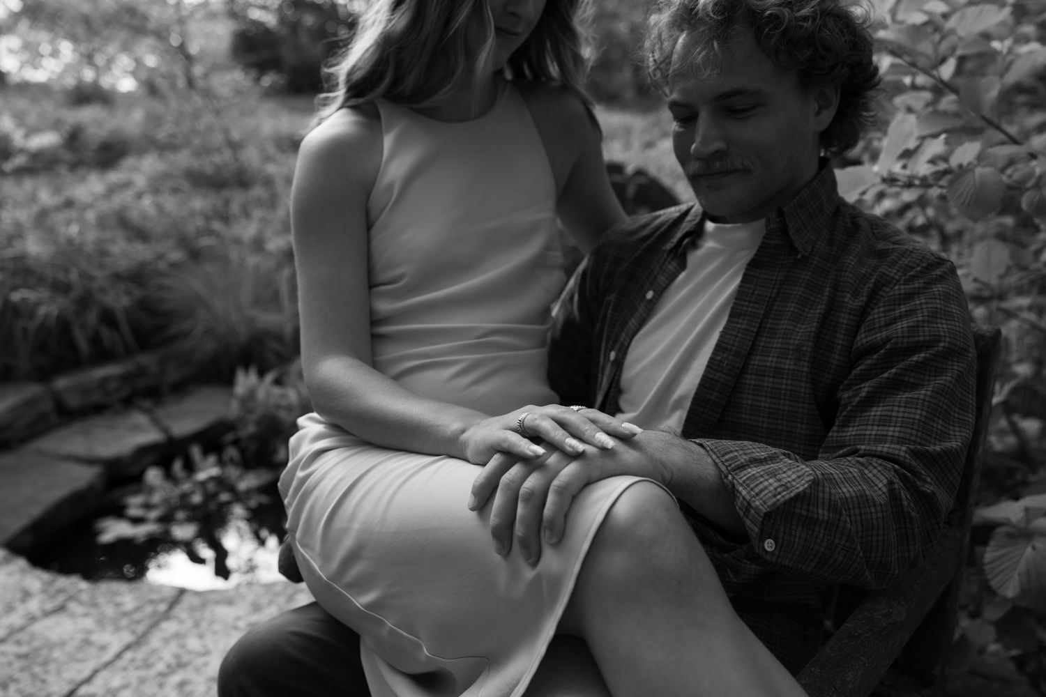 An intimate black and white portrait of a couple sharing a quiet moment outdoors.