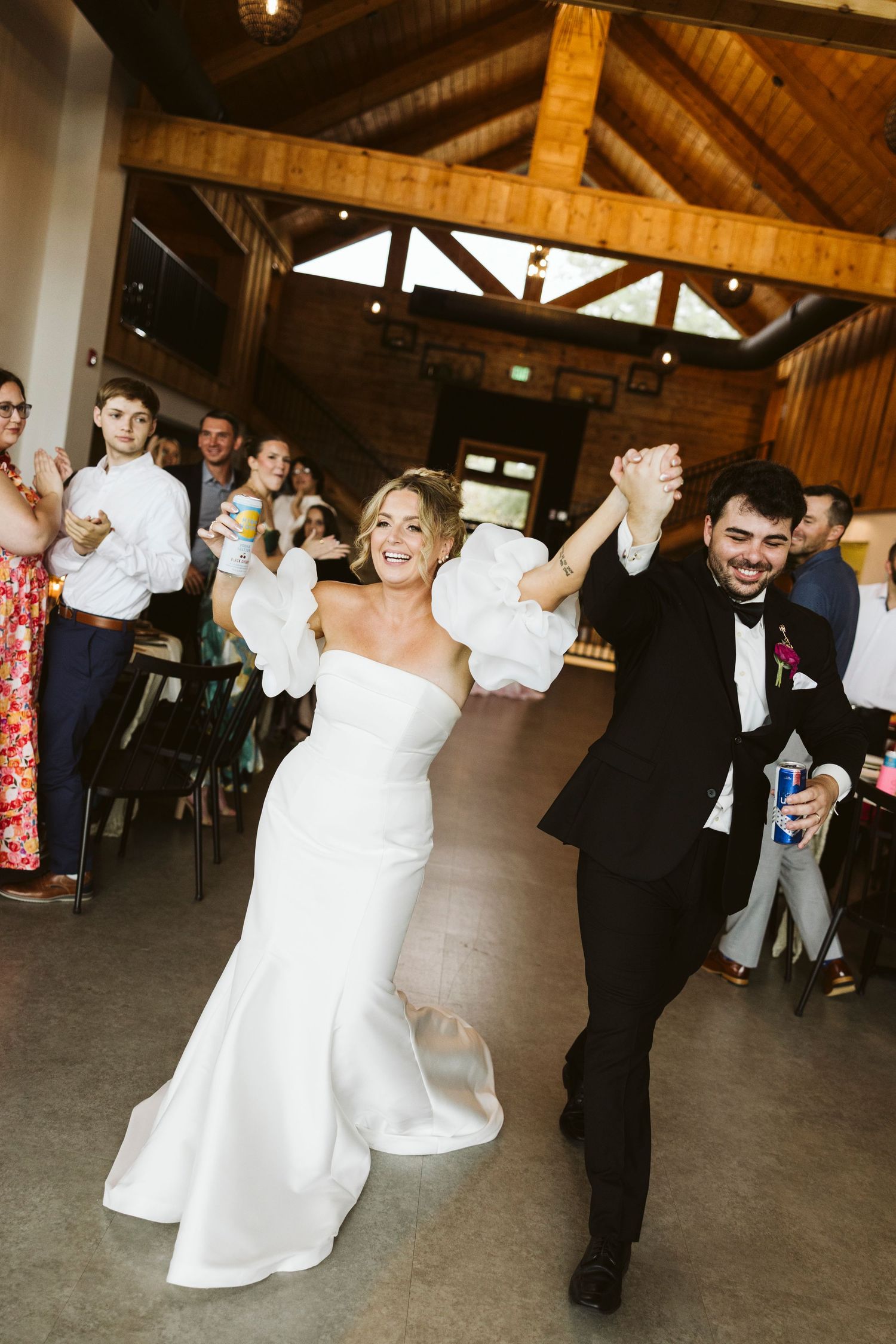 Wedding guests dancing and celebrating in a rustic wooden barn reception venue.