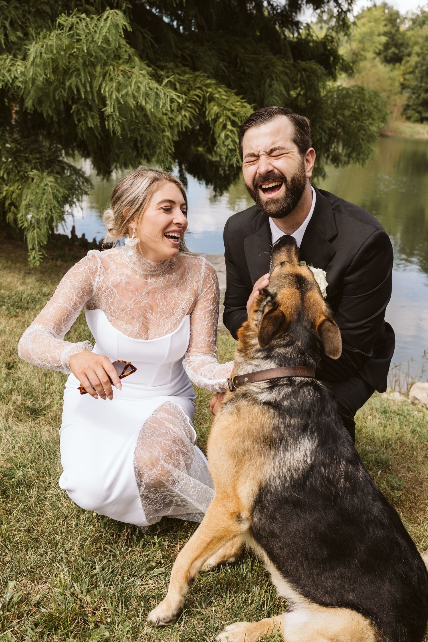 A couple sits by a lake with their German Shepherd dog in a series of joyful outdoor portraits.