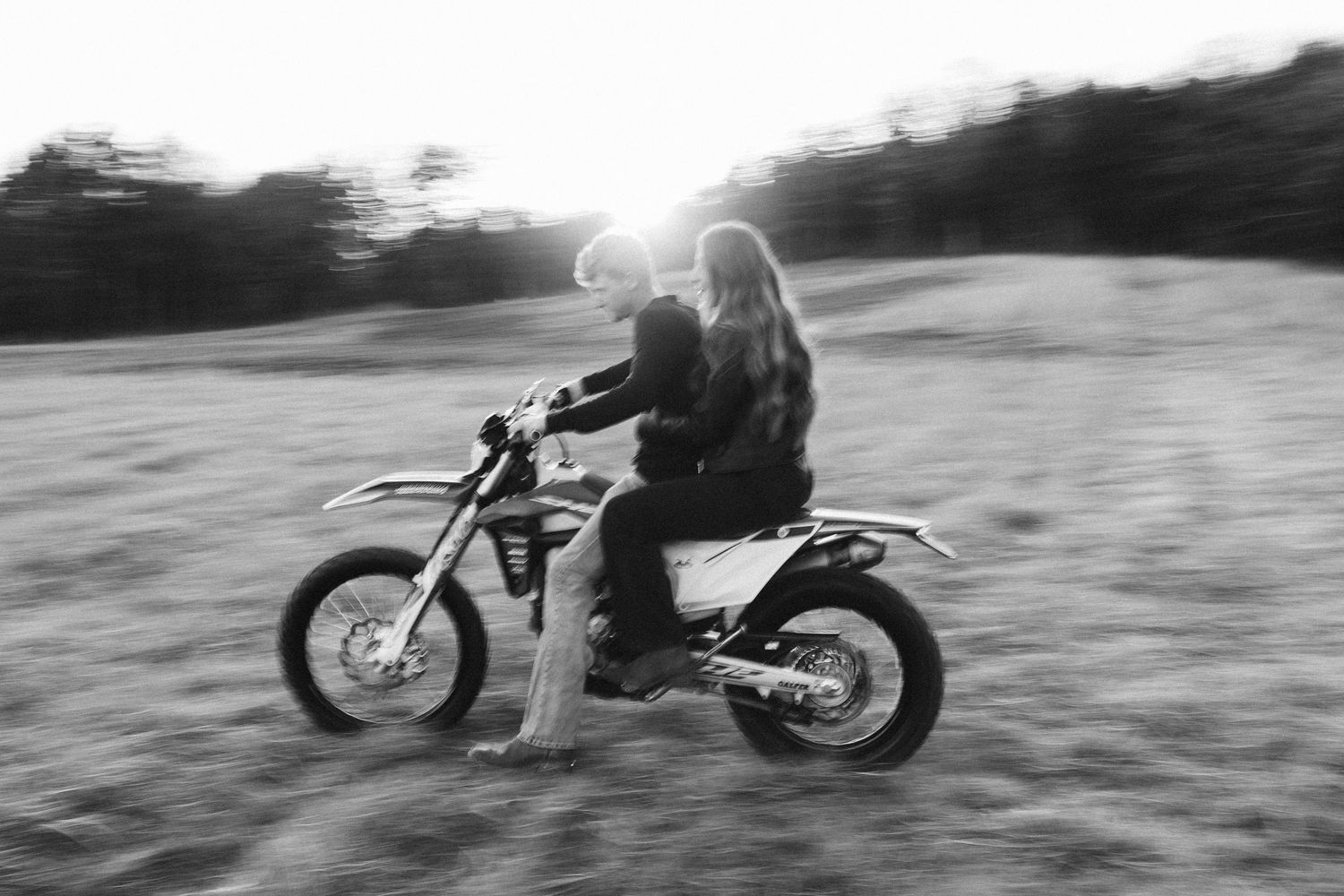 A person riding a dirt bike through a field in black and white motion blur photography.