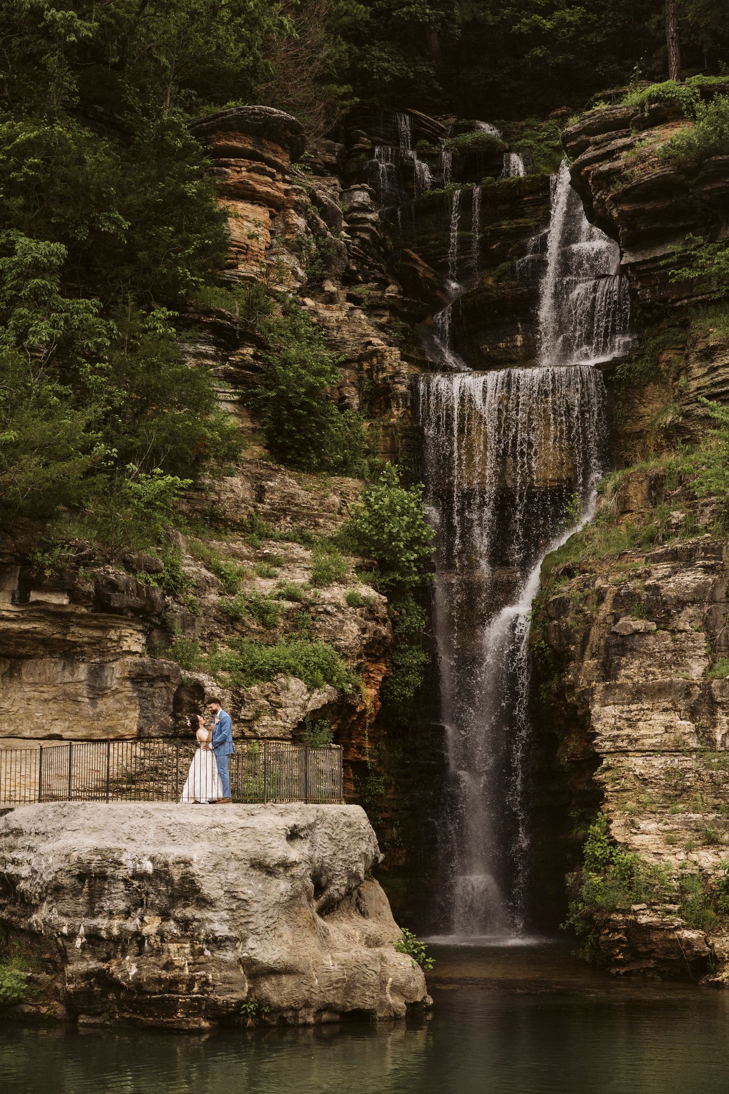 A scenic waterfall cascades down rocky cliffs creating a stunning backdrop for wedding photography.