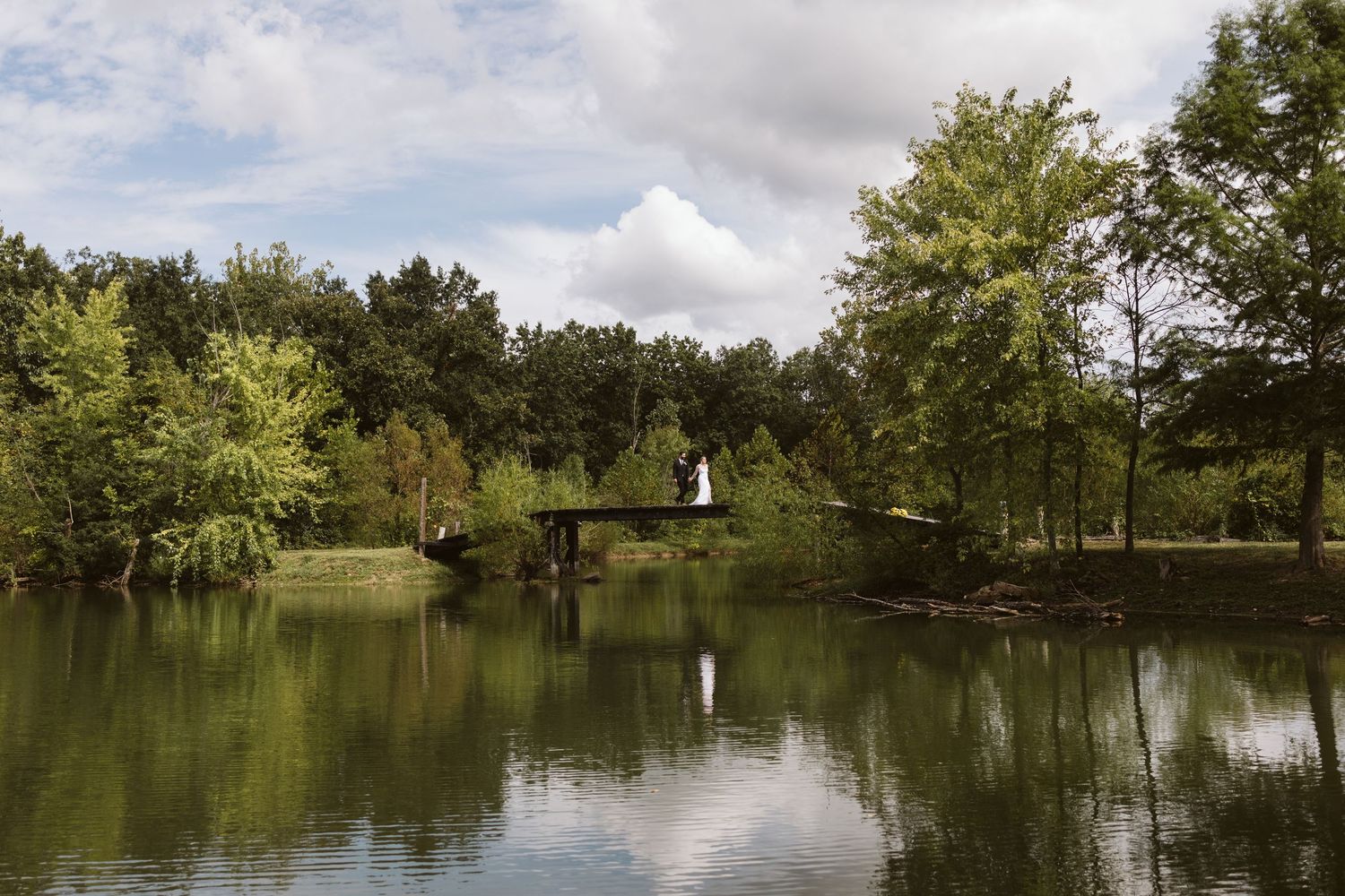 Serene lake landscape with trees reflecting on calm water under cloudy skies.