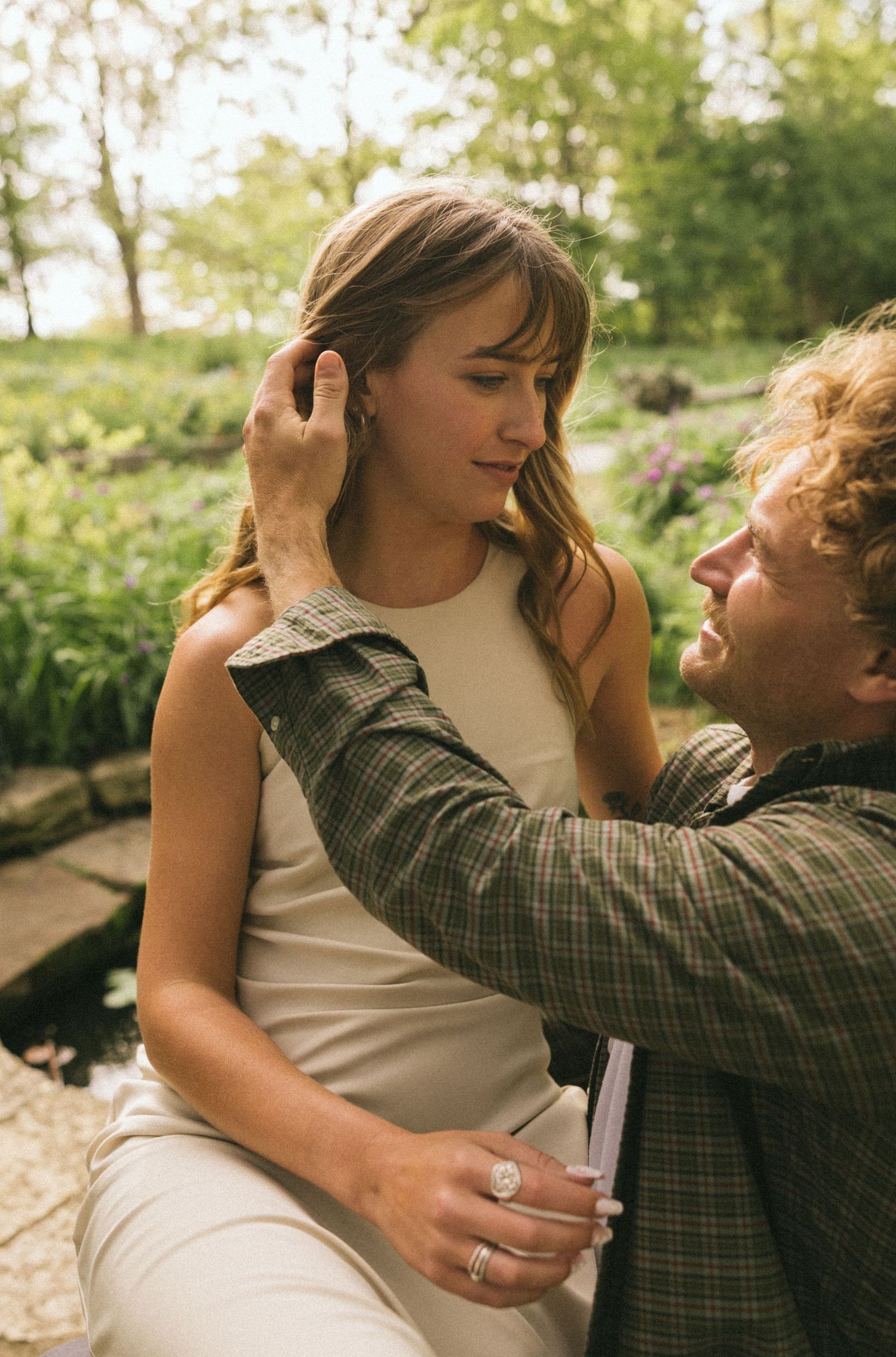 An intimate moment captured between a couple sitting outdoors in natural lighting.