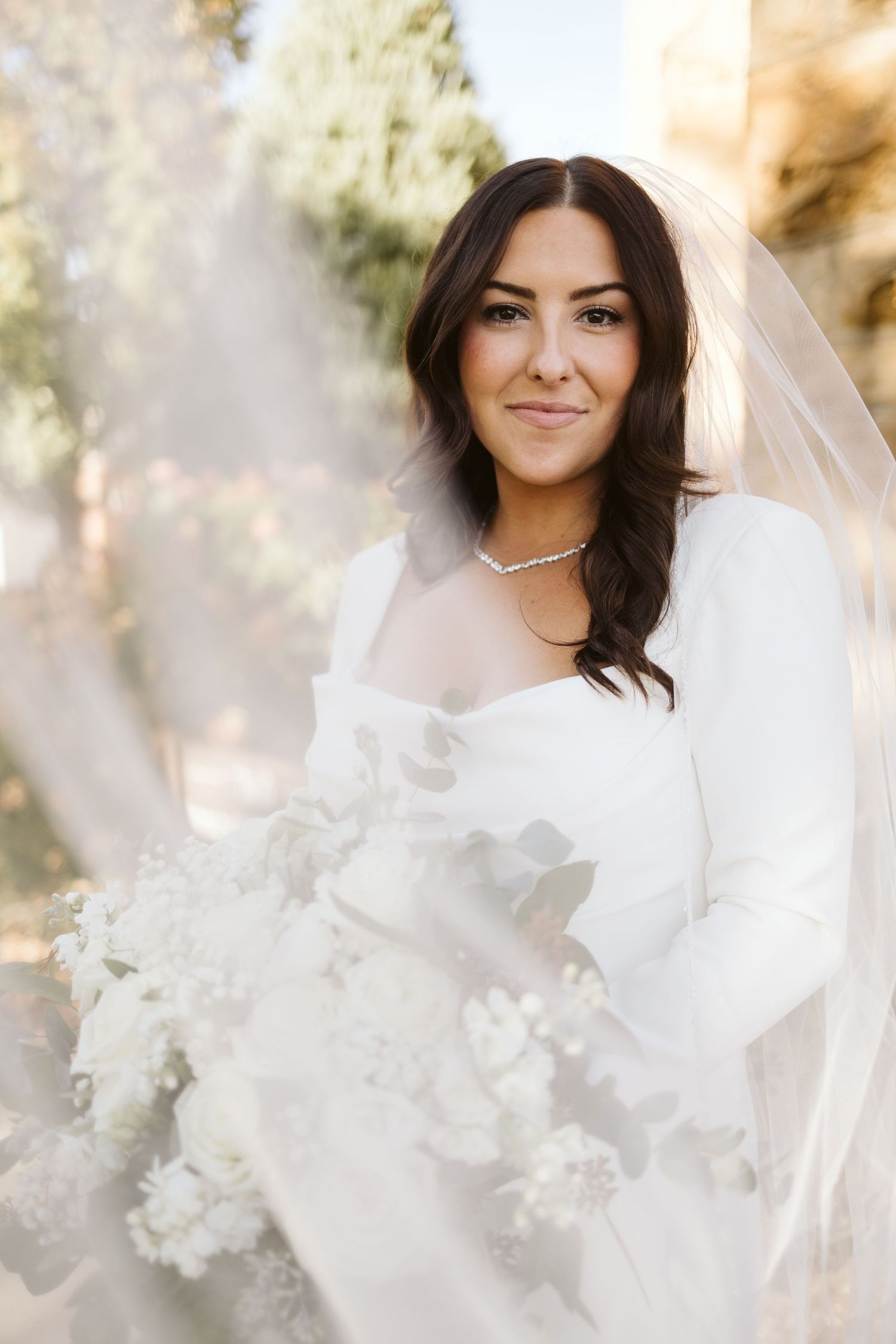 A bridal portrait featuring a radiant bride in a white dress holding a bouquet of flowers.