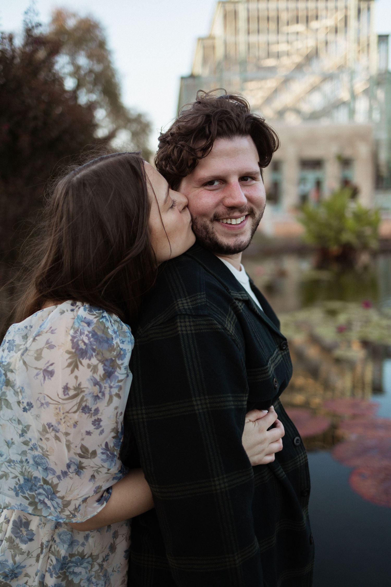 A romantic moment shared outdoors against an urban backdrop.