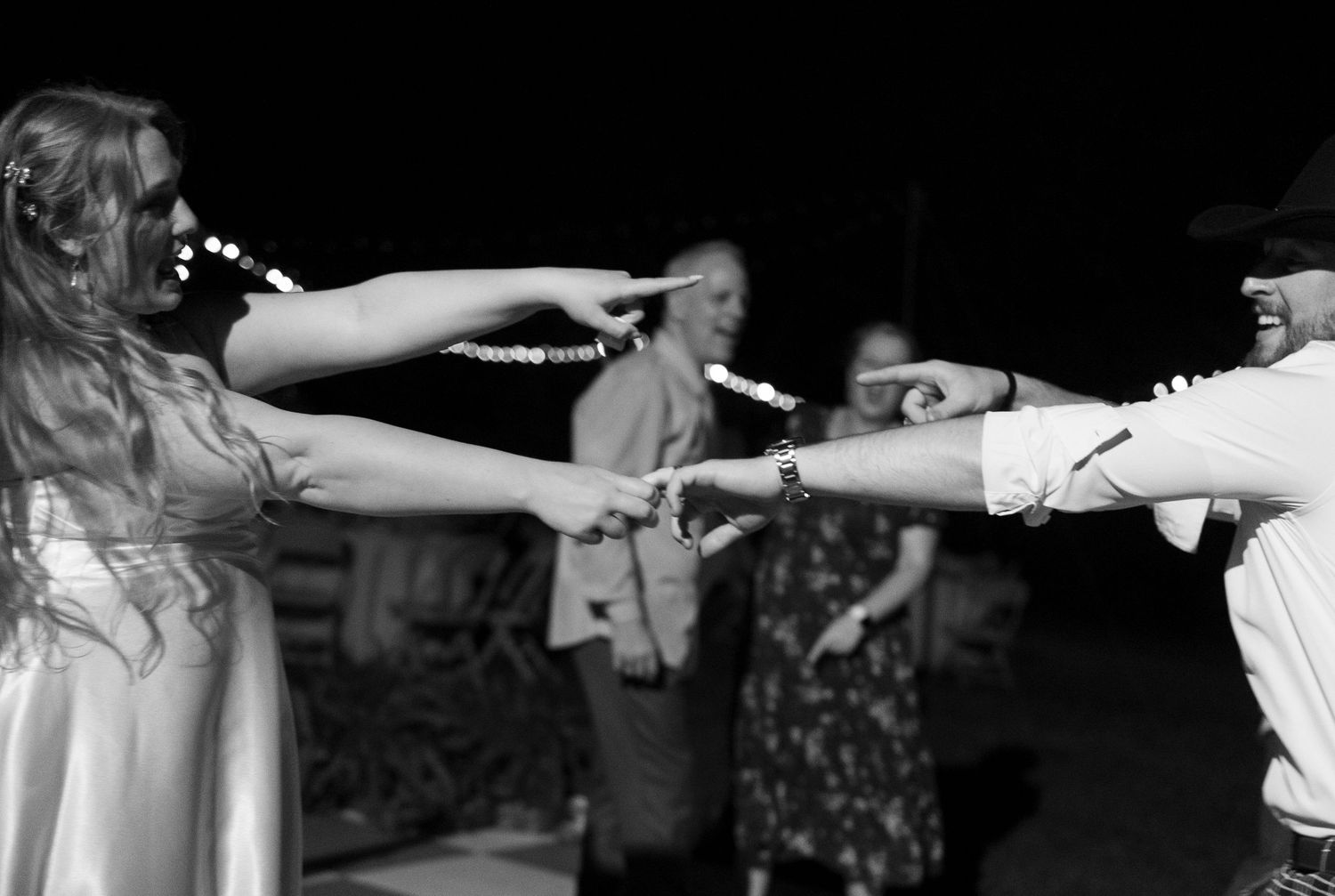 A dramatic black and white photo shows the alignment of multiple hands reaching and pointing toward each other.