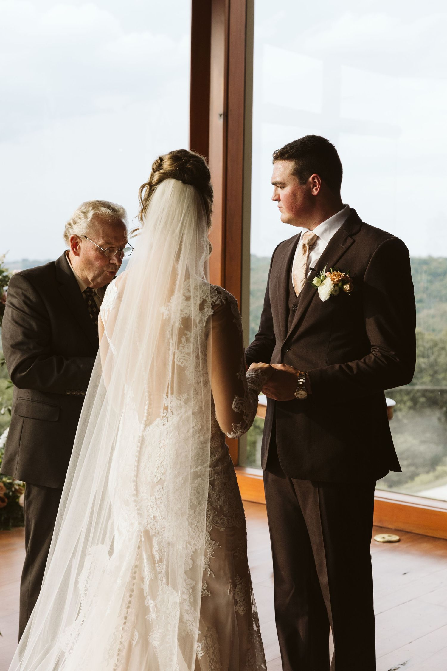 A wedding ceremony taking place in a scenic venue with large windows overlooking mountains.