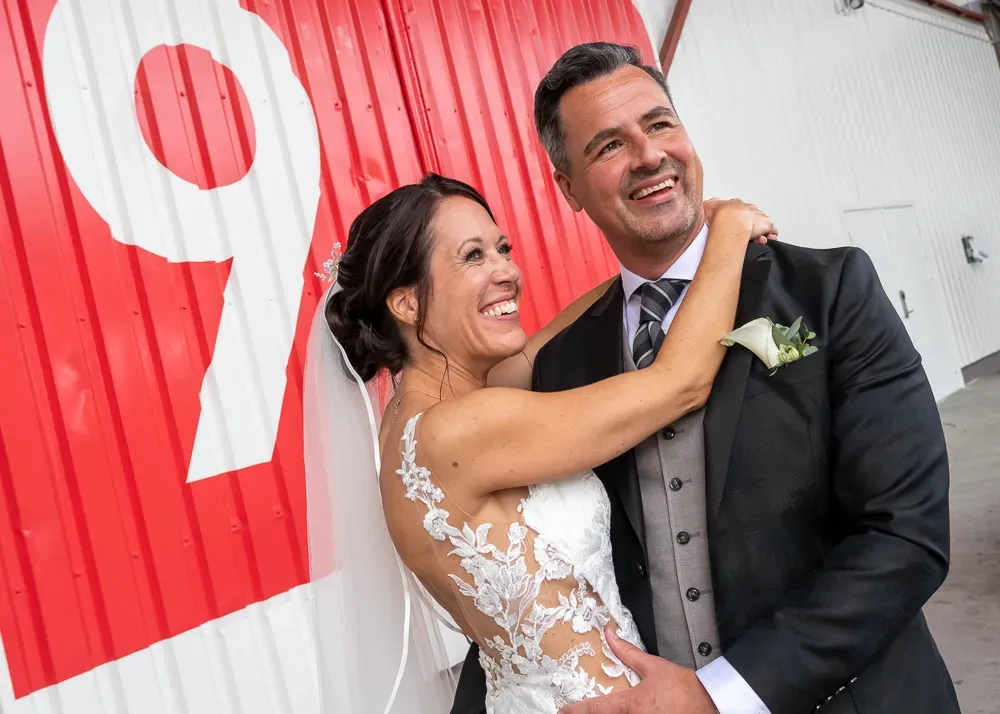 A couple shares a joyful moment against a red wall with the number 9.