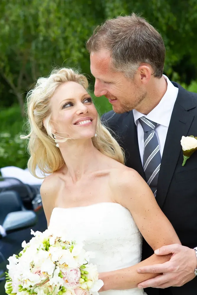 Romantic outdoor wedding portraits with a white floral bouquet against lush green scenery.