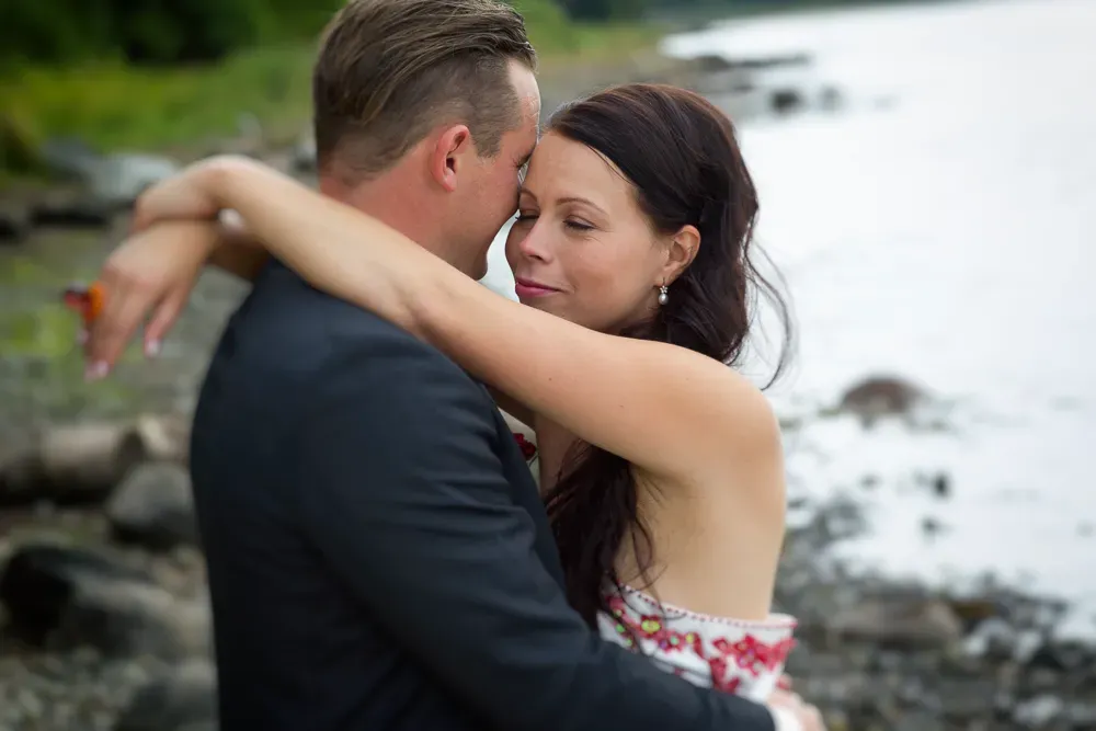 Romantic waterfront embrace between wedding couple.