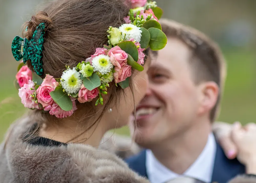 A flower crown adorns a bride's head as she shares an intimate moment outdoors.