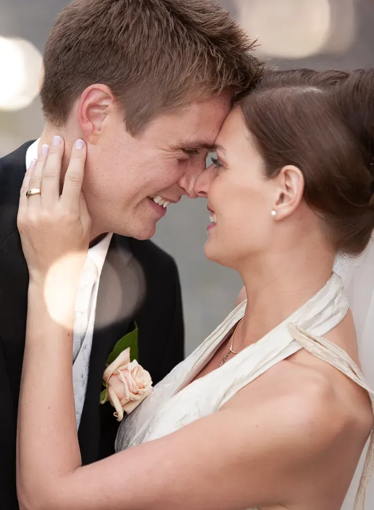 A romantic close-up of a couple touching foreheads in formal wedding attire.