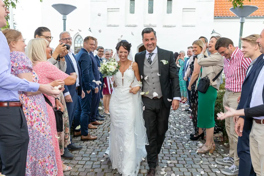 Wedding couple walking through a crowd of guests on a cobblestone path.