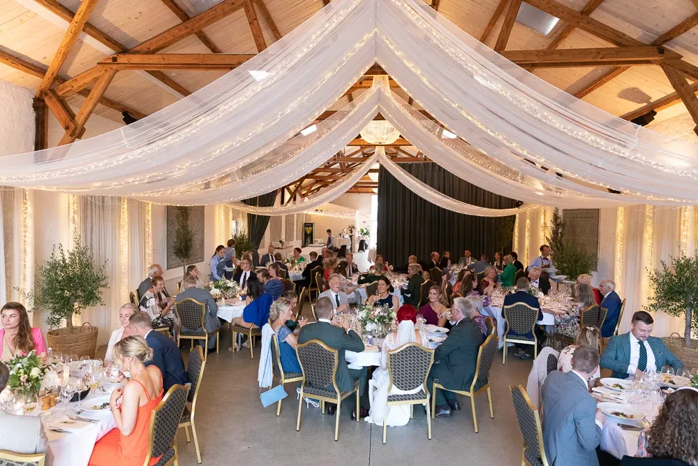 Wedding reception venue decorated with white draping and elegant table settings.