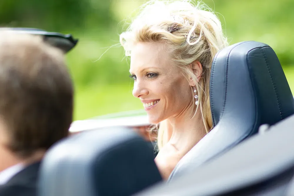Happy couple riding in a convertible on their wedding day.