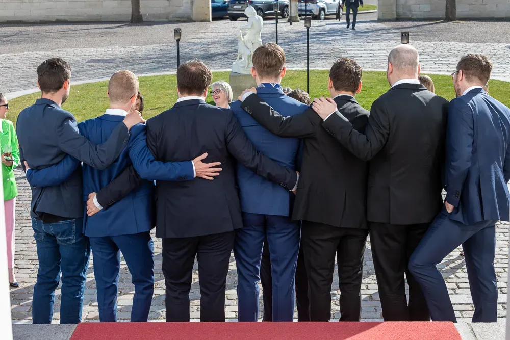 Back view of groomsmen standing in a row wearing matching navy suits.