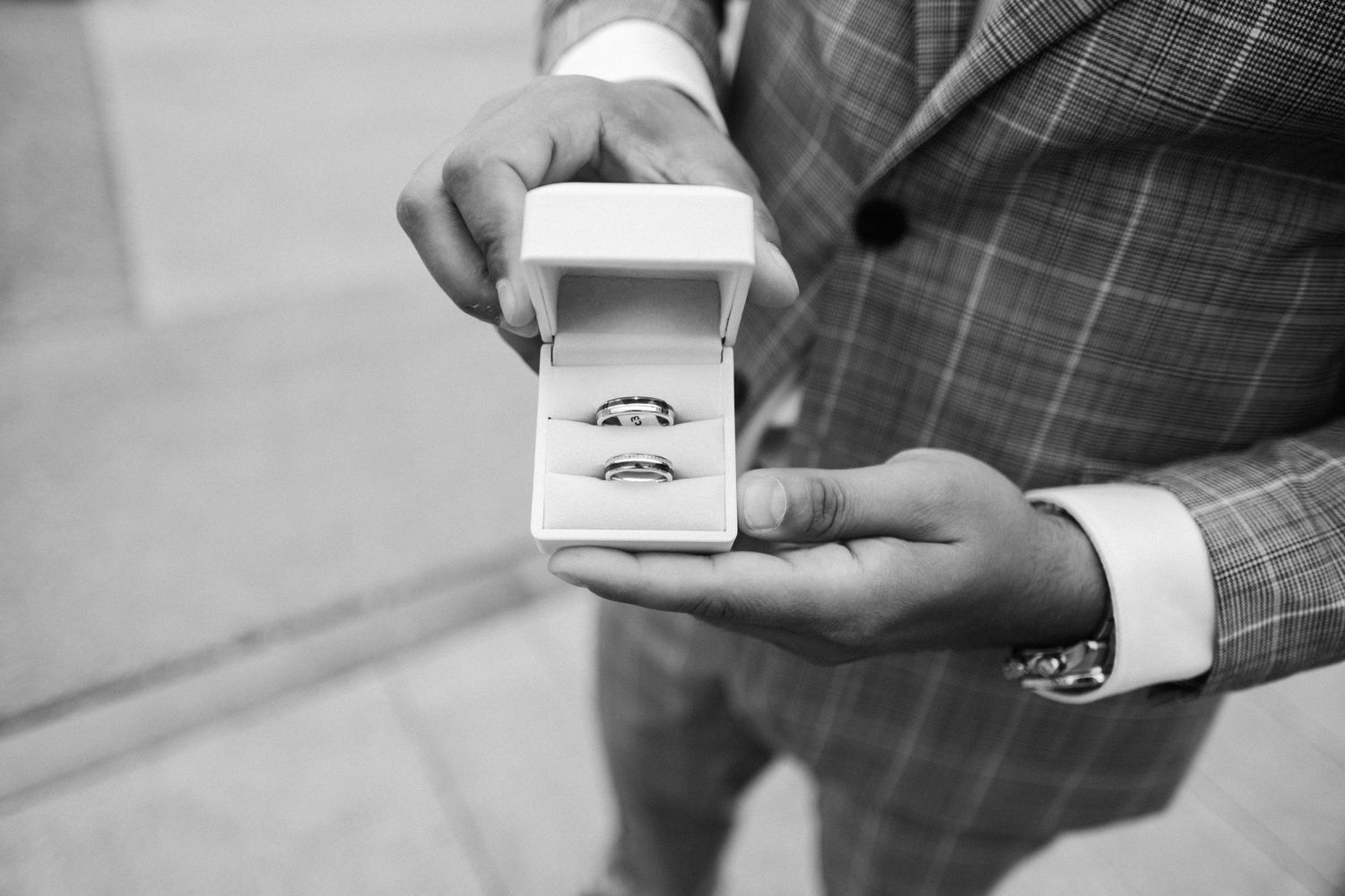 Hands displaying an engagement ring box in black and white photography.