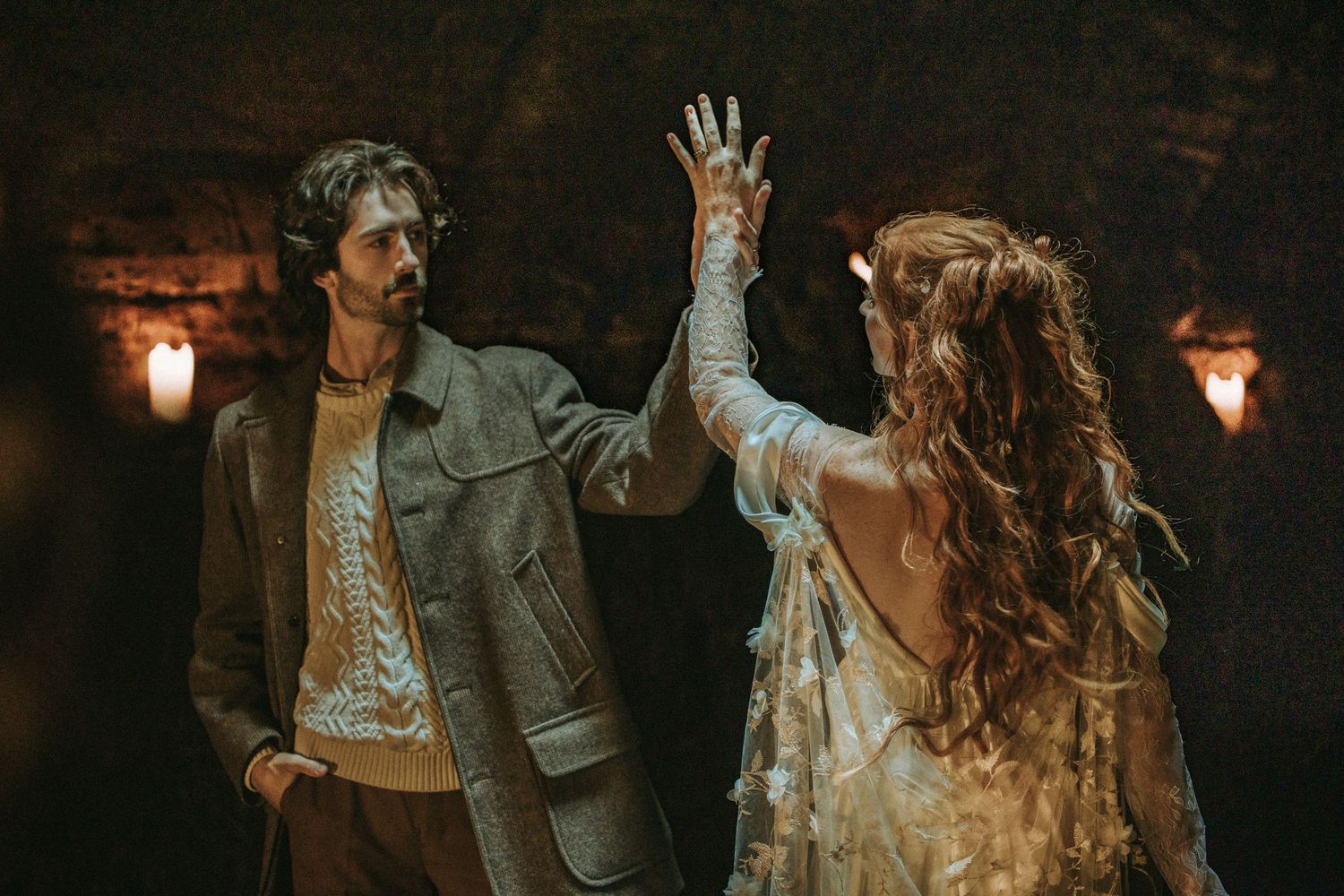 A couple dances together in moody lighting, dressed in bohemian style clothing with ethereal romantic atmosphere.