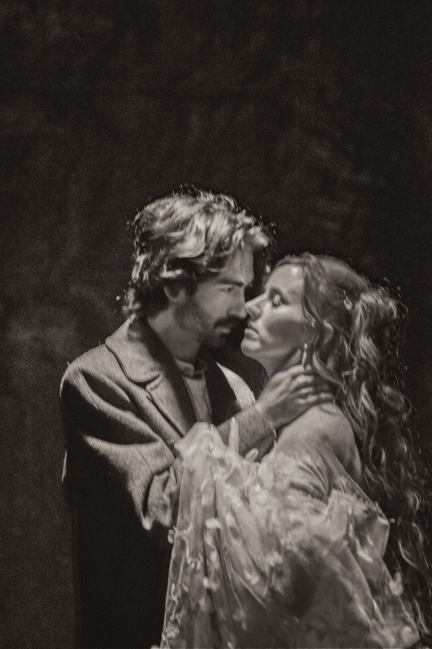 A dramatic black and white portrait of a couple in an intimate embrace showing passion and romance.